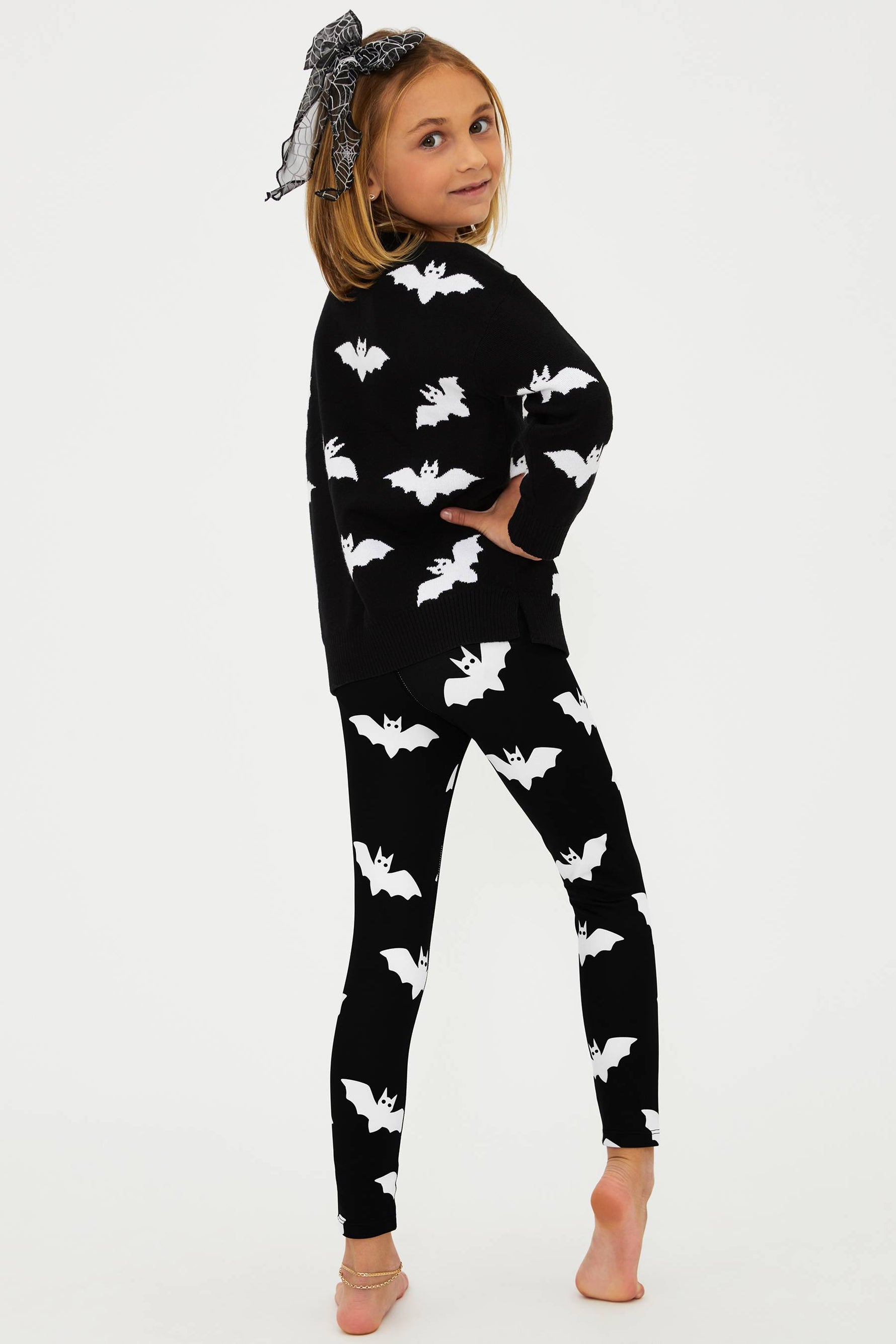 Child wearing a black outfit with white bat patterns on a white background