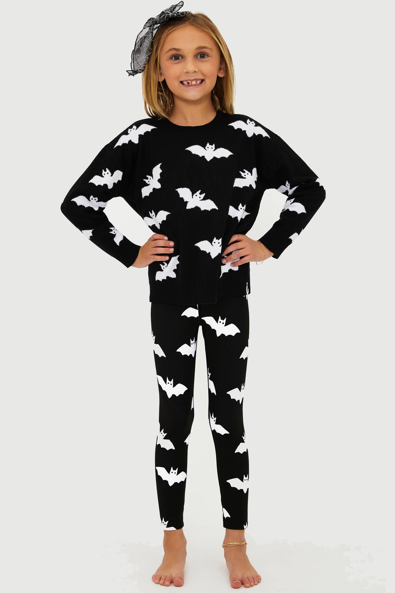 Child wearing a black outfit with white bat patterns on a plain background