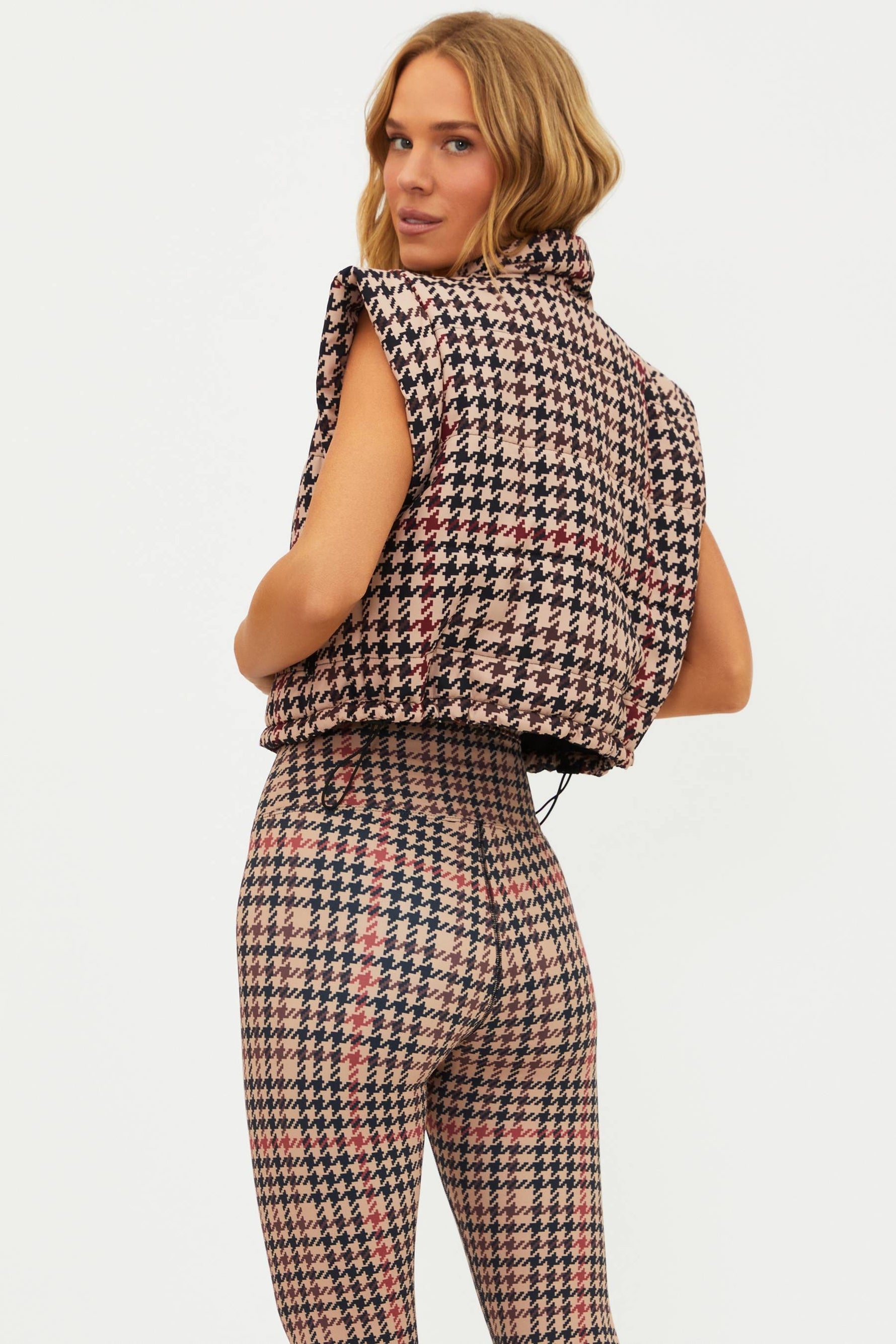 Woman wearing a houndstooth patterned outfit on a white background