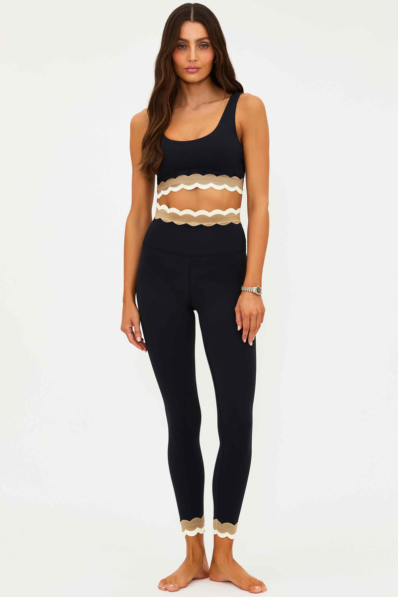 Woman wearing a black outfit with scalloped details on a white background