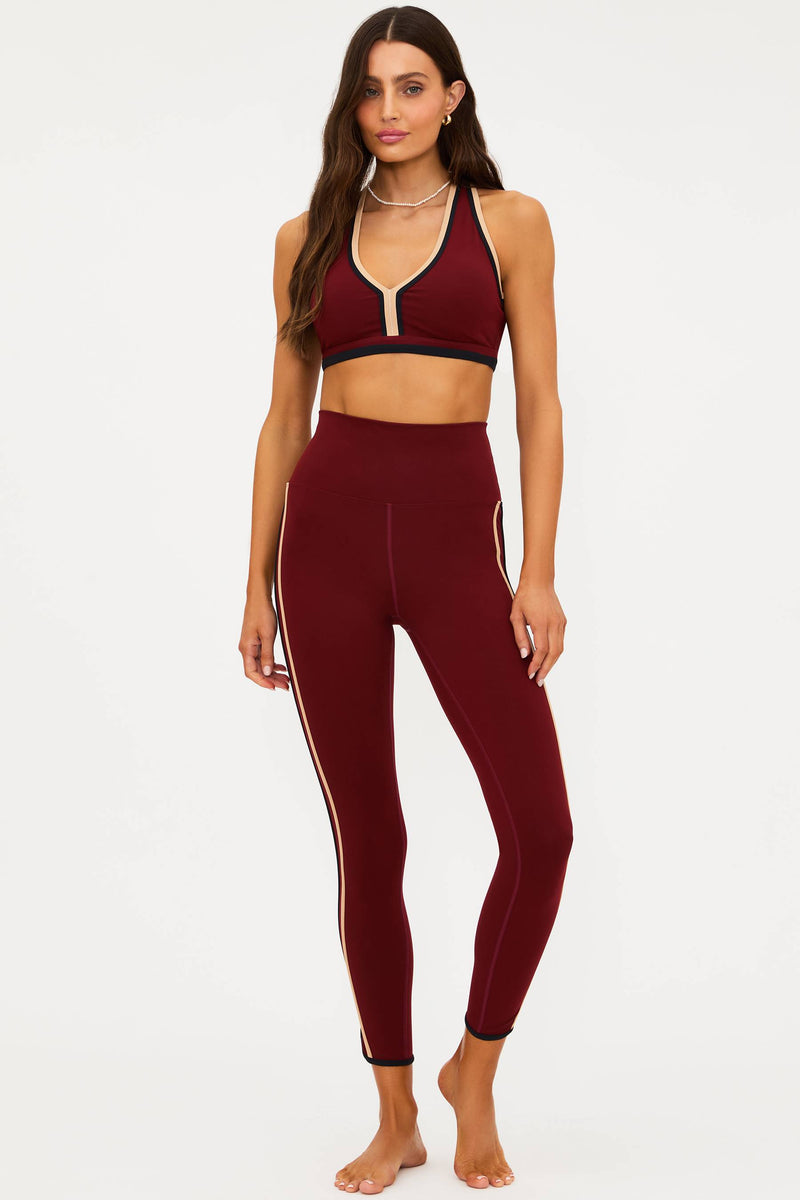 Woman wearing a burgundy sports bra and leggings set on a white background