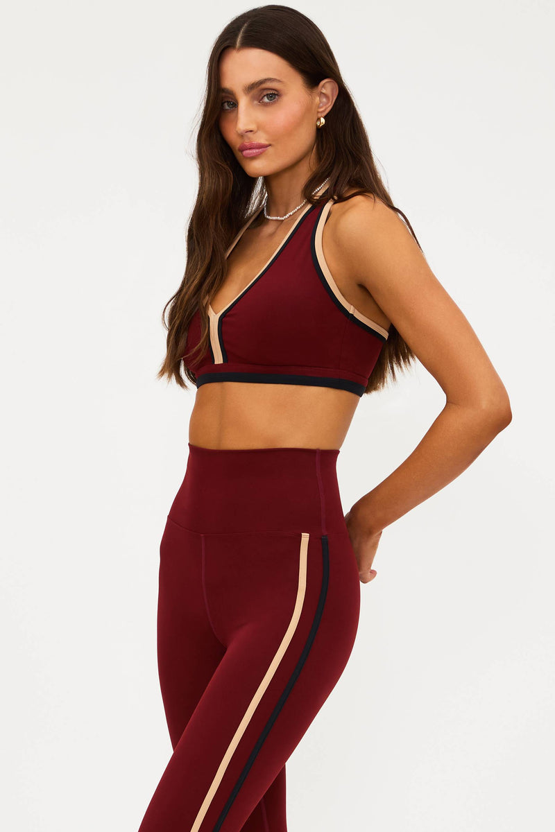 Woman wearing a burgundy sports bra and leggings set on a white background
