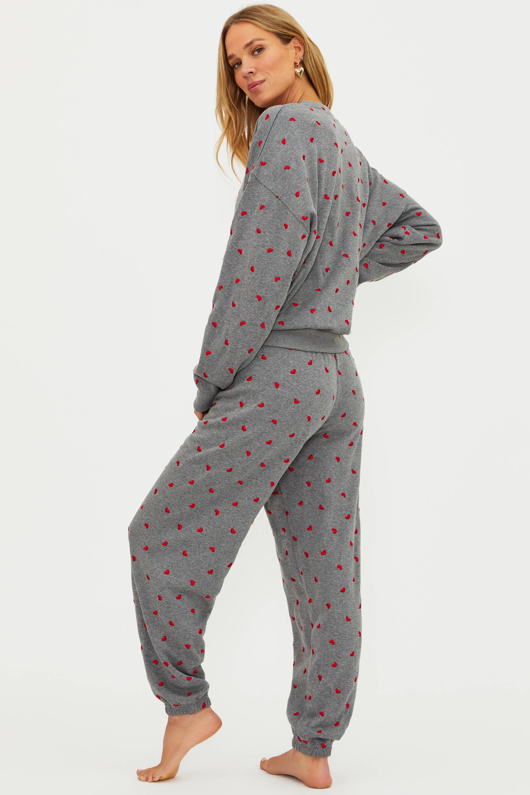 Woman wearing gray pajamas with red patterns on a white background