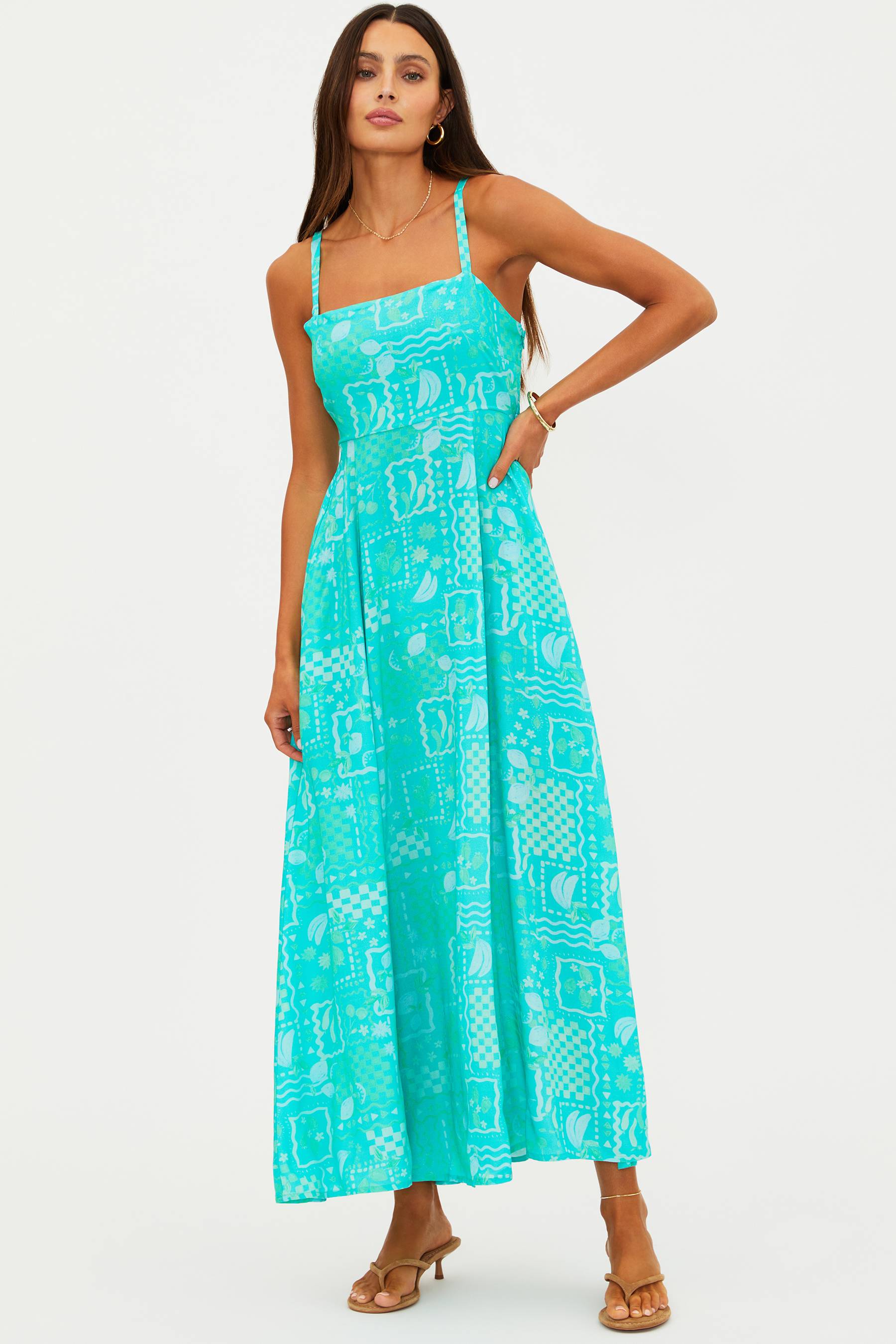 Woman wearing a turquoise dress with a white pattern on a white background