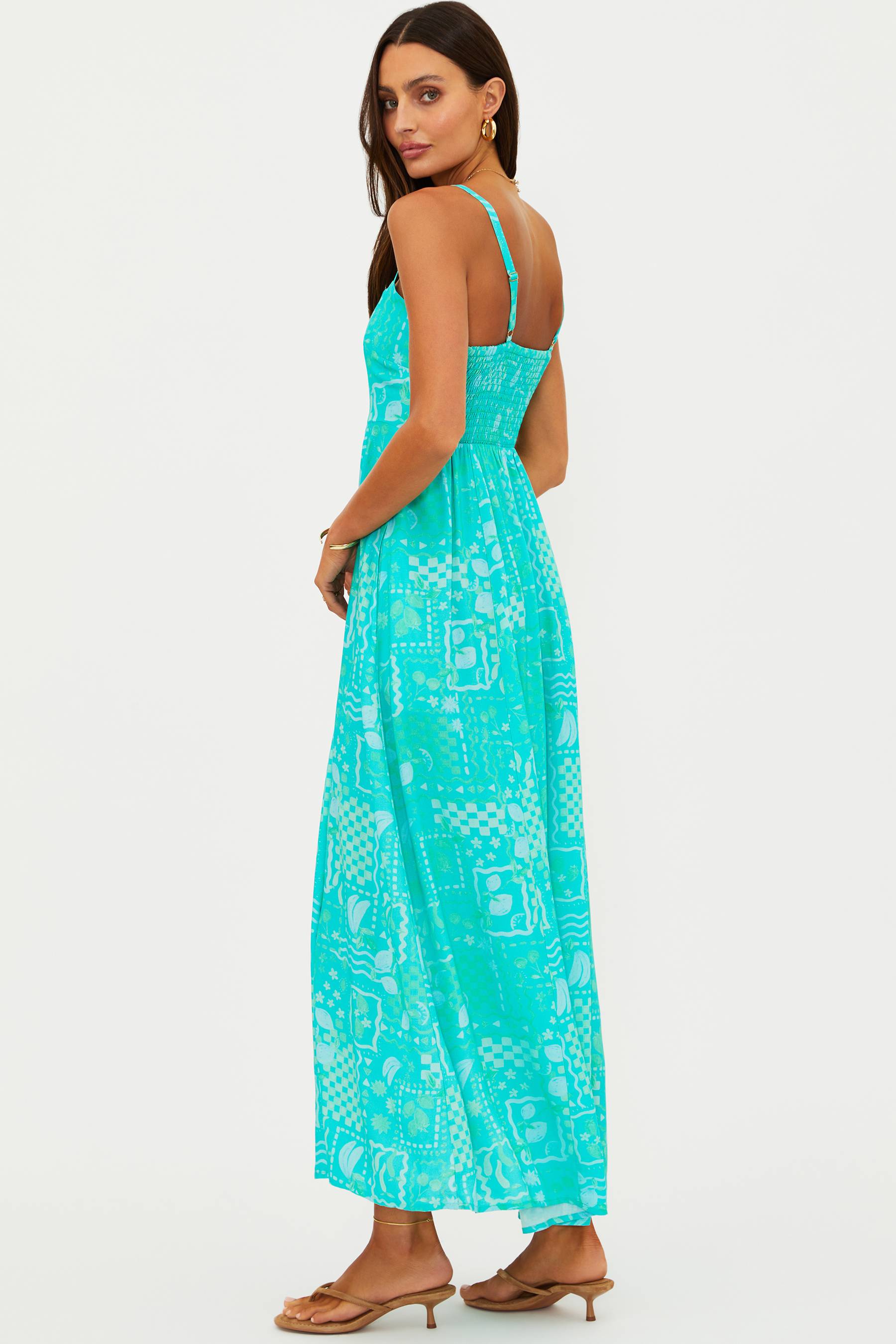 Woman wearing a turquoise dress with a geometric pattern on a white background