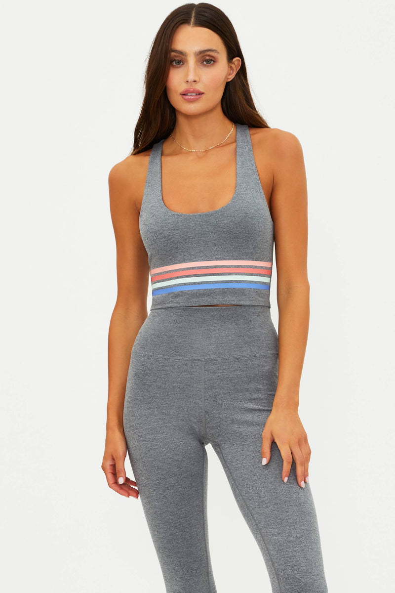 Woman wearing a gray athletic outfit with a colorful stripe on a white background
