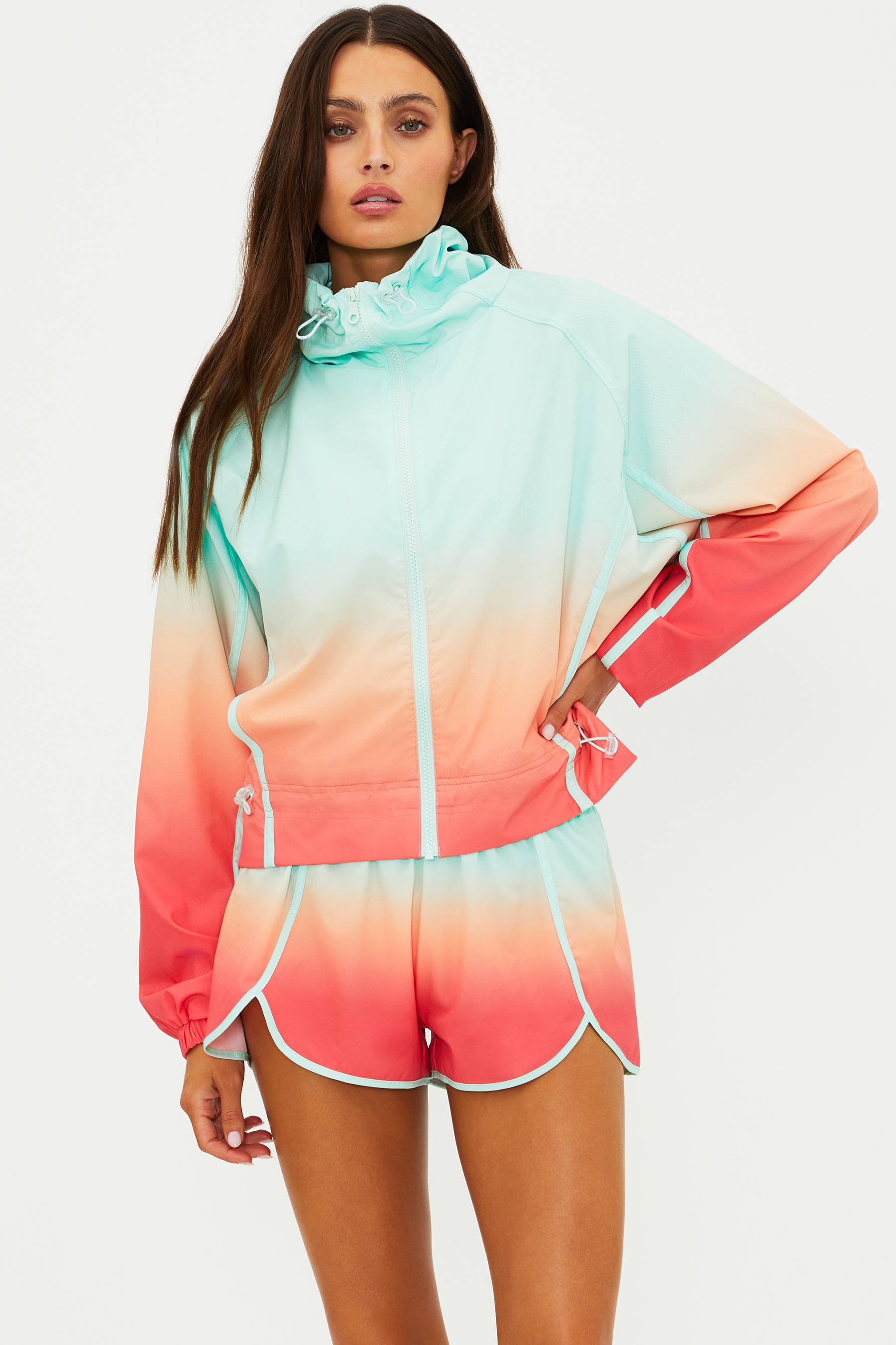 Woman wearing a colorful gradient hoodie and shorts set on a white background