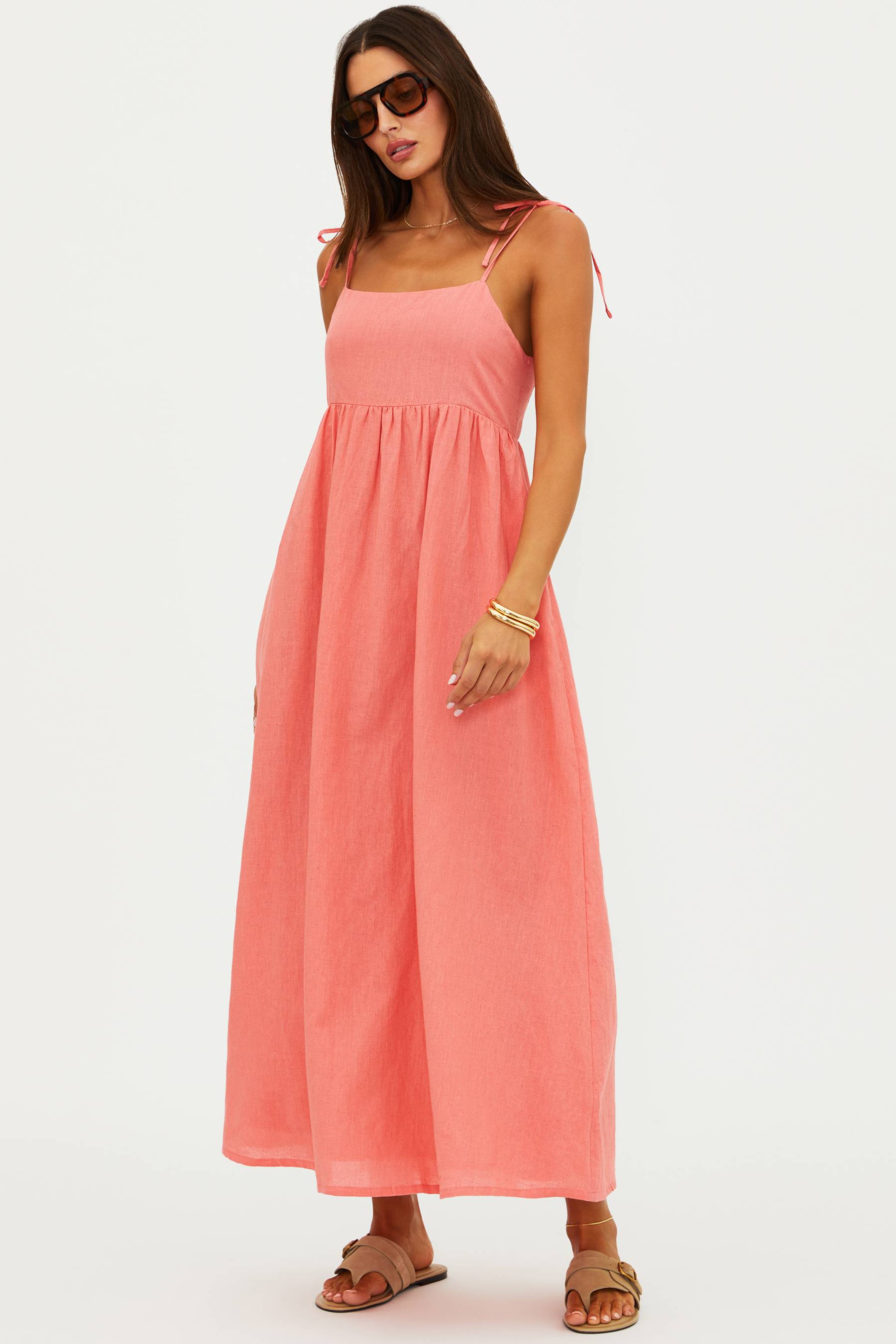 Woman wearing a coral pink dress on a white background