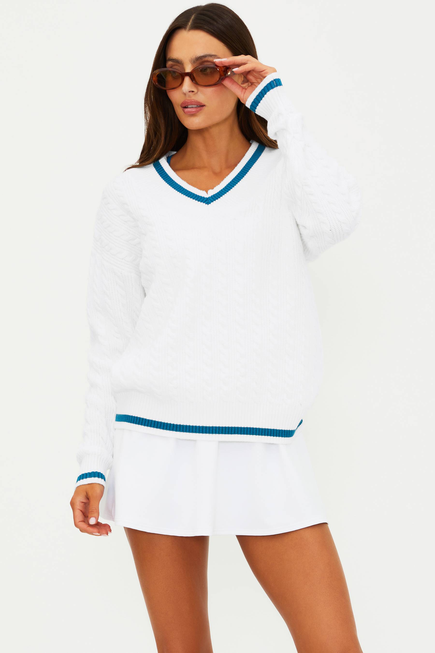 Woman wearing a white sweater dress with blue trim on a white background