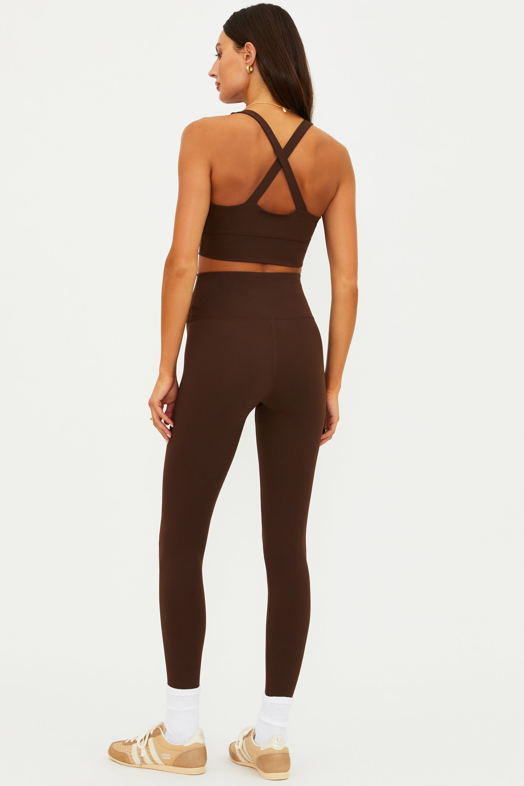 Woman wearing a brown sports bra and leggings set on a white background