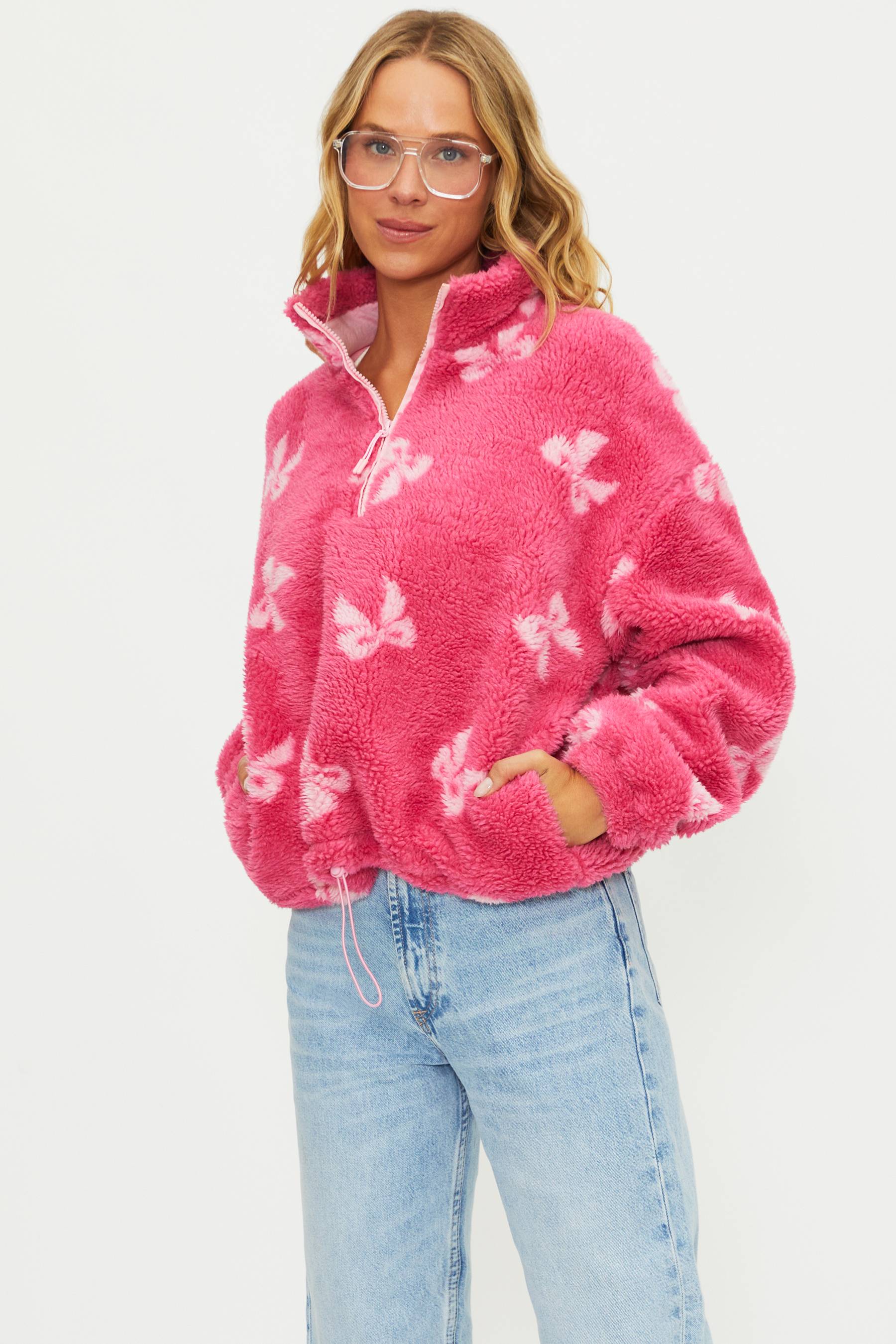Woman wearing a pink fleece pullover with butterfly pattern on a white background