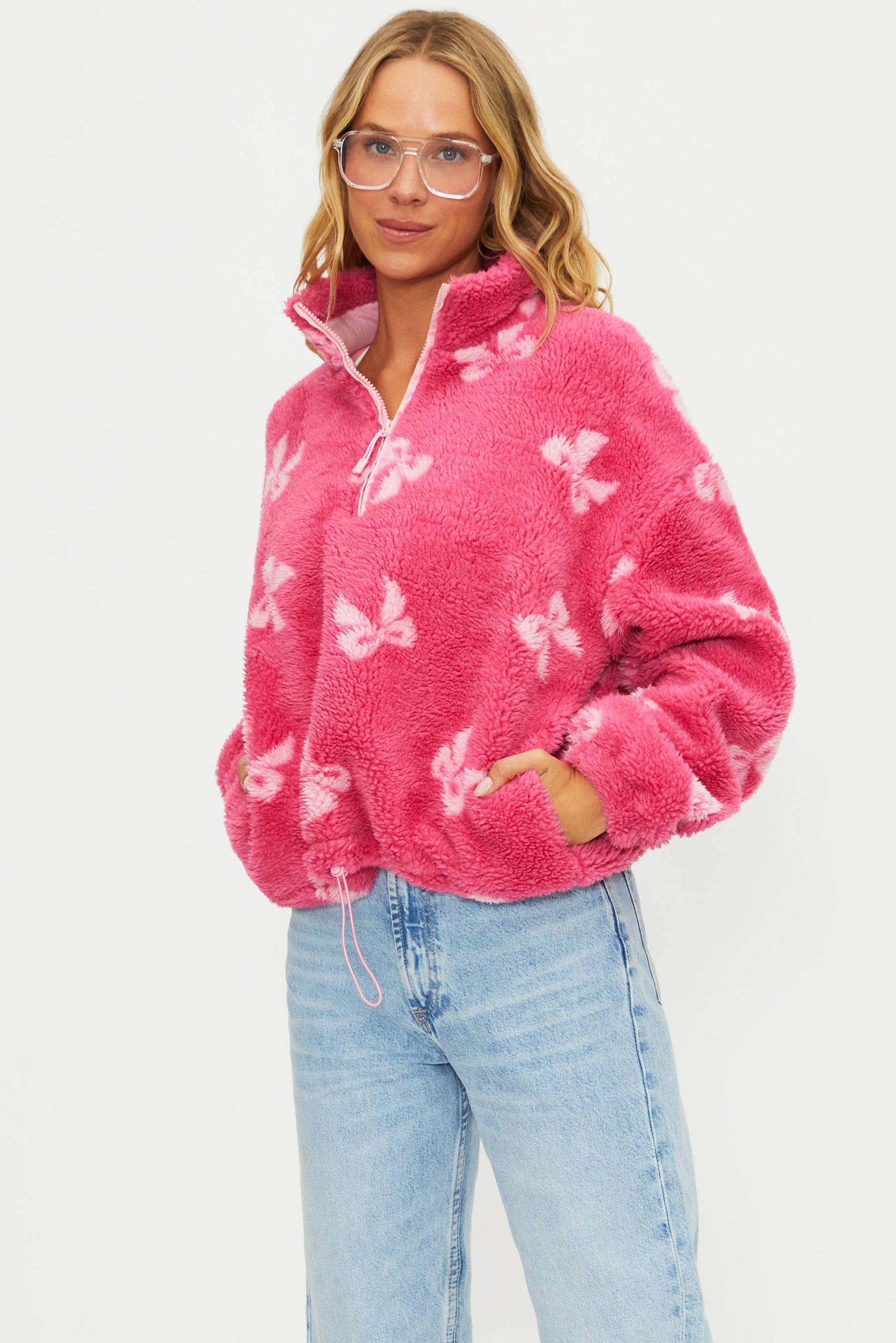 Woman wearing a pink fleece pullover with butterfly pattern on a white background
