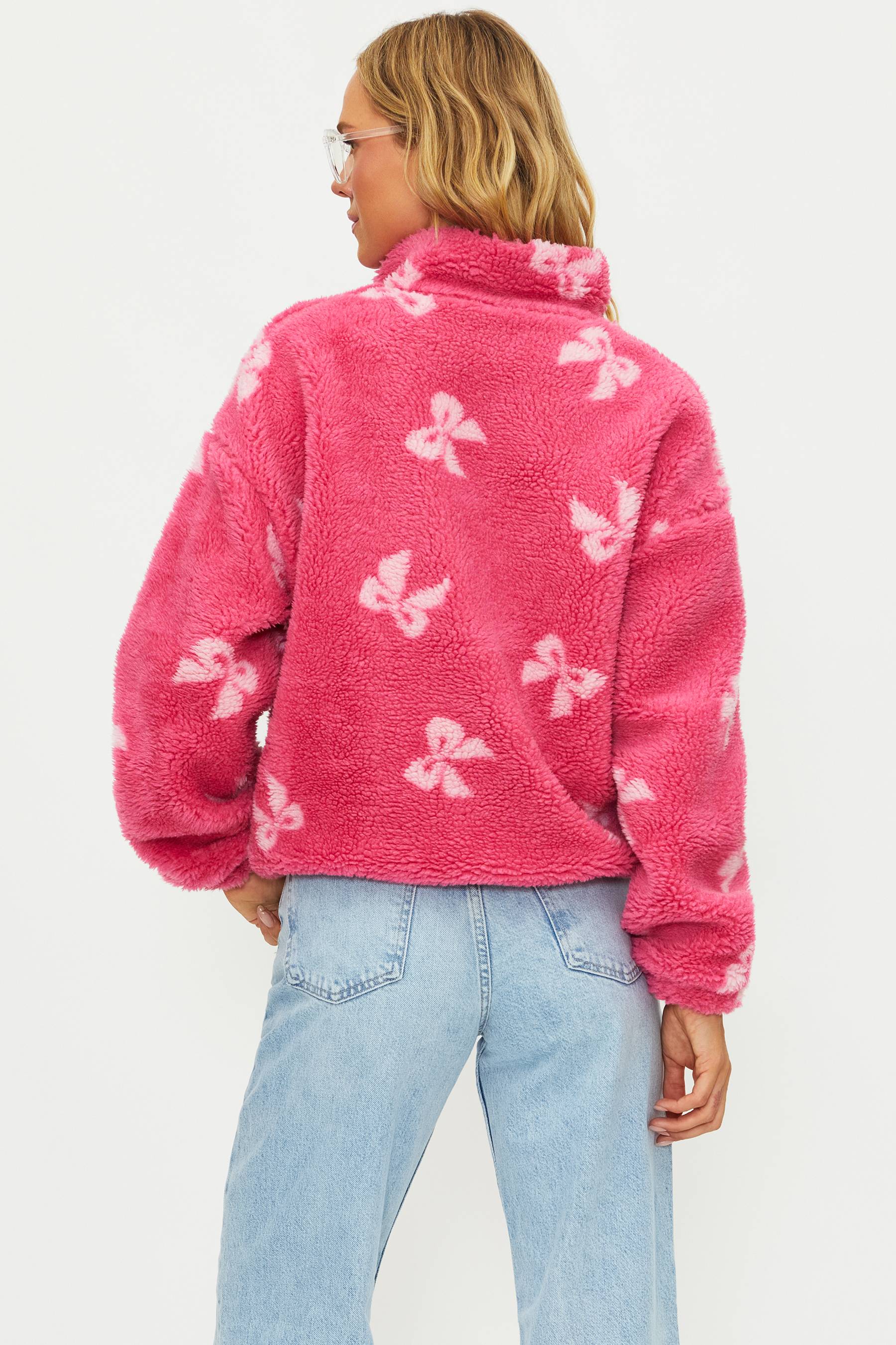 Person wearing a pink fleece jacket with butterfly patterns on a white background