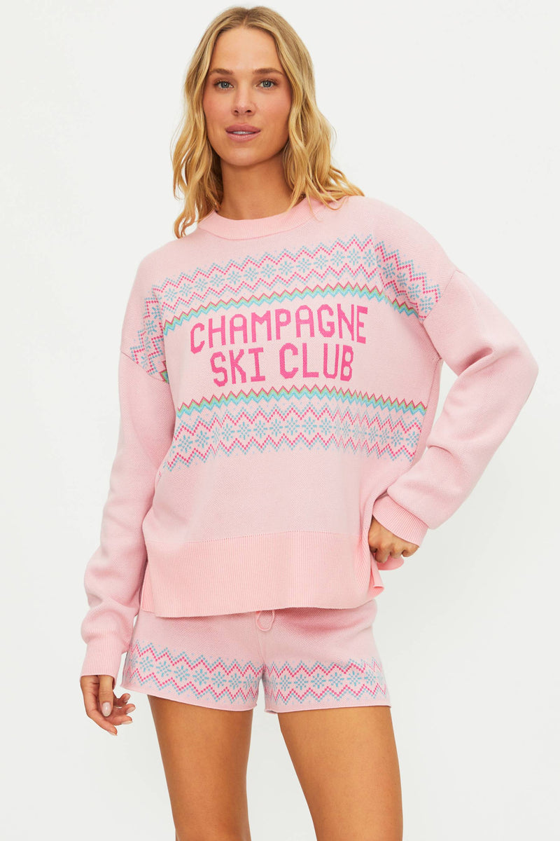 Woman wearing a pink 'Champagne Ski Club' outfit with matching top and shorts on a white background