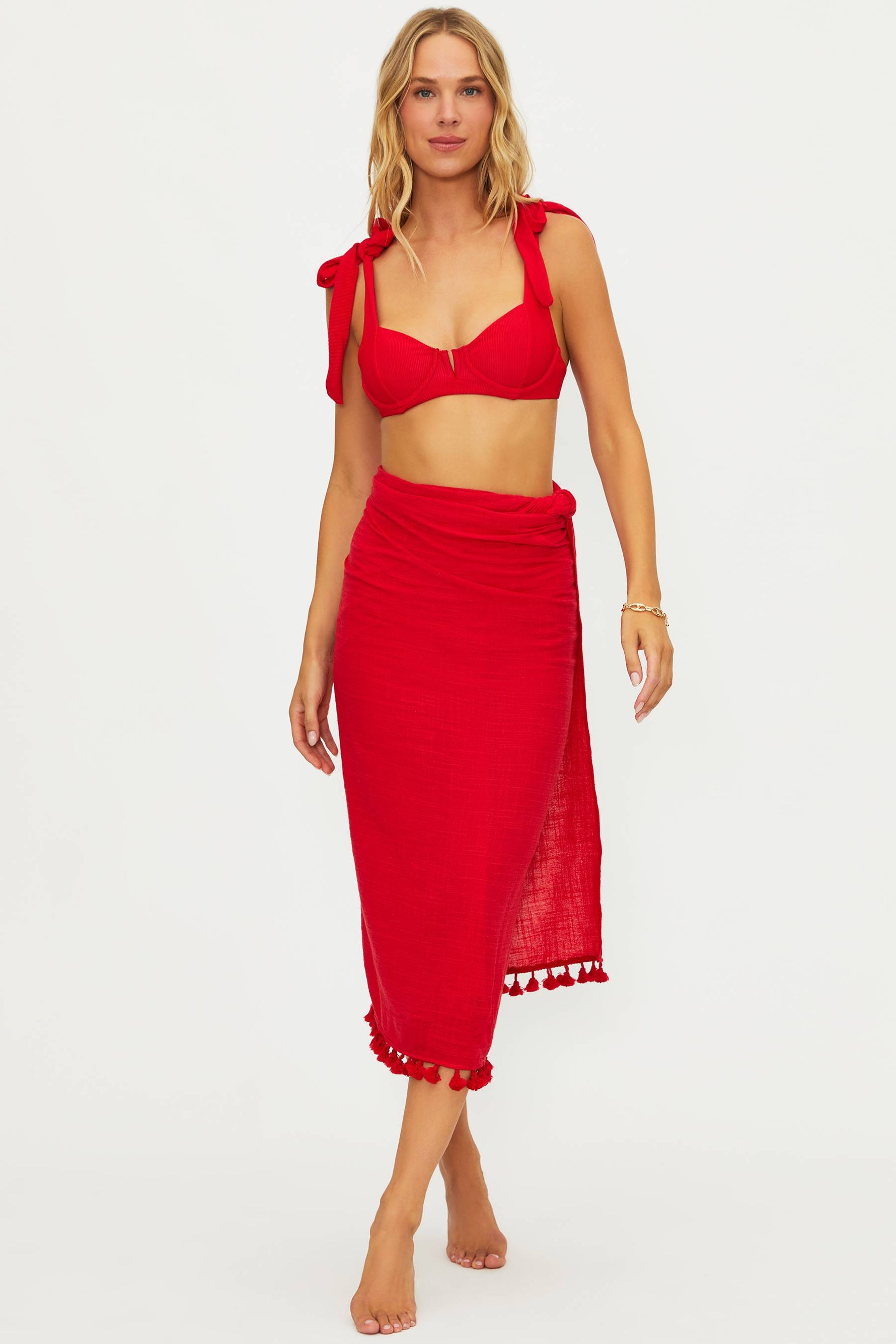 Woman wearing a red bikini set with a matching skirt on a white background