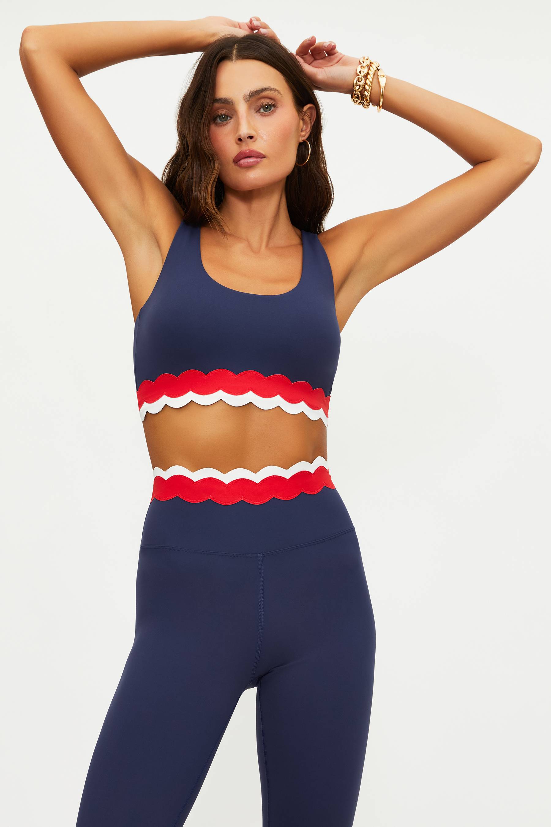 Woman wearing a navy sports bra with red and white trim on a plain background