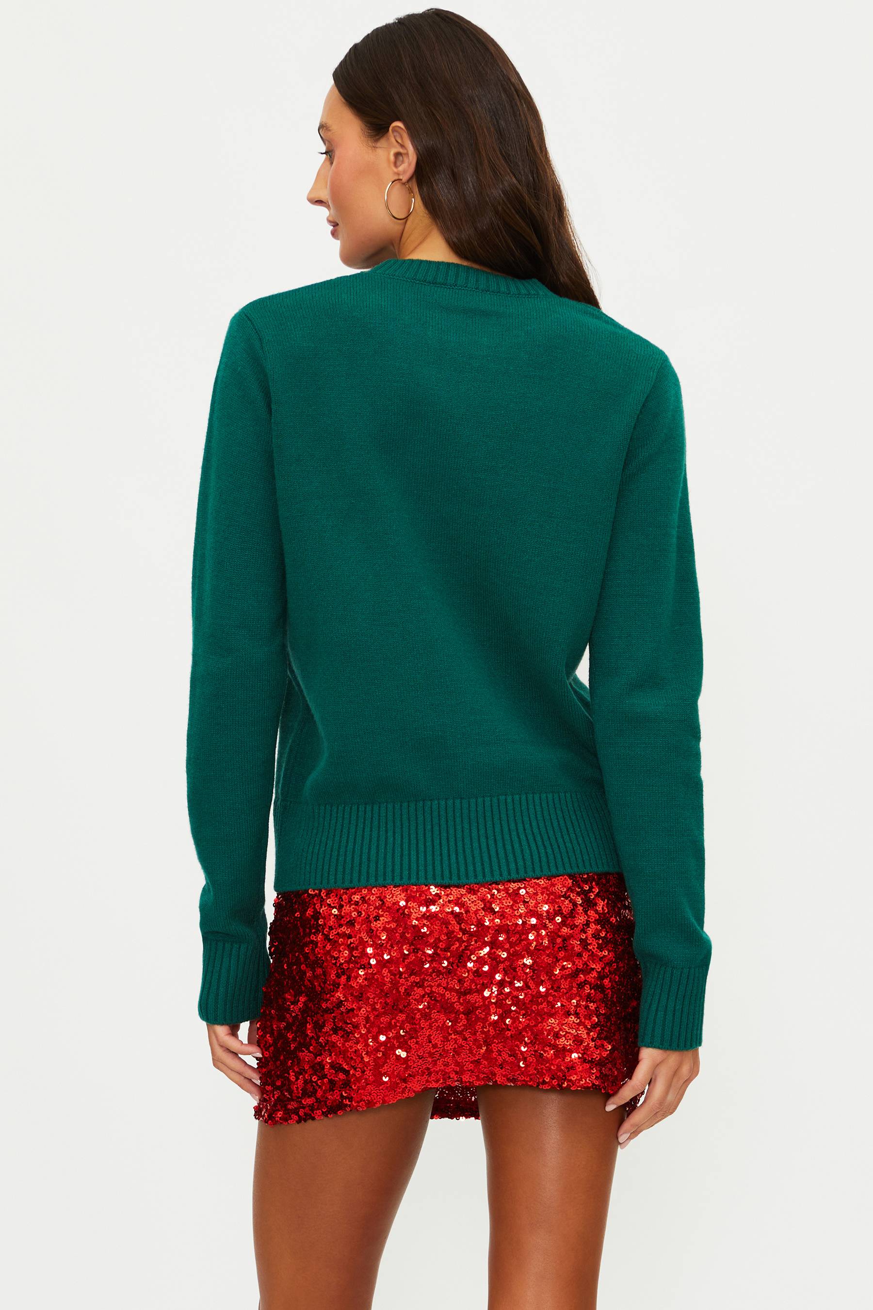 Woman wearing a green sweater and red sequin skirt on a white background