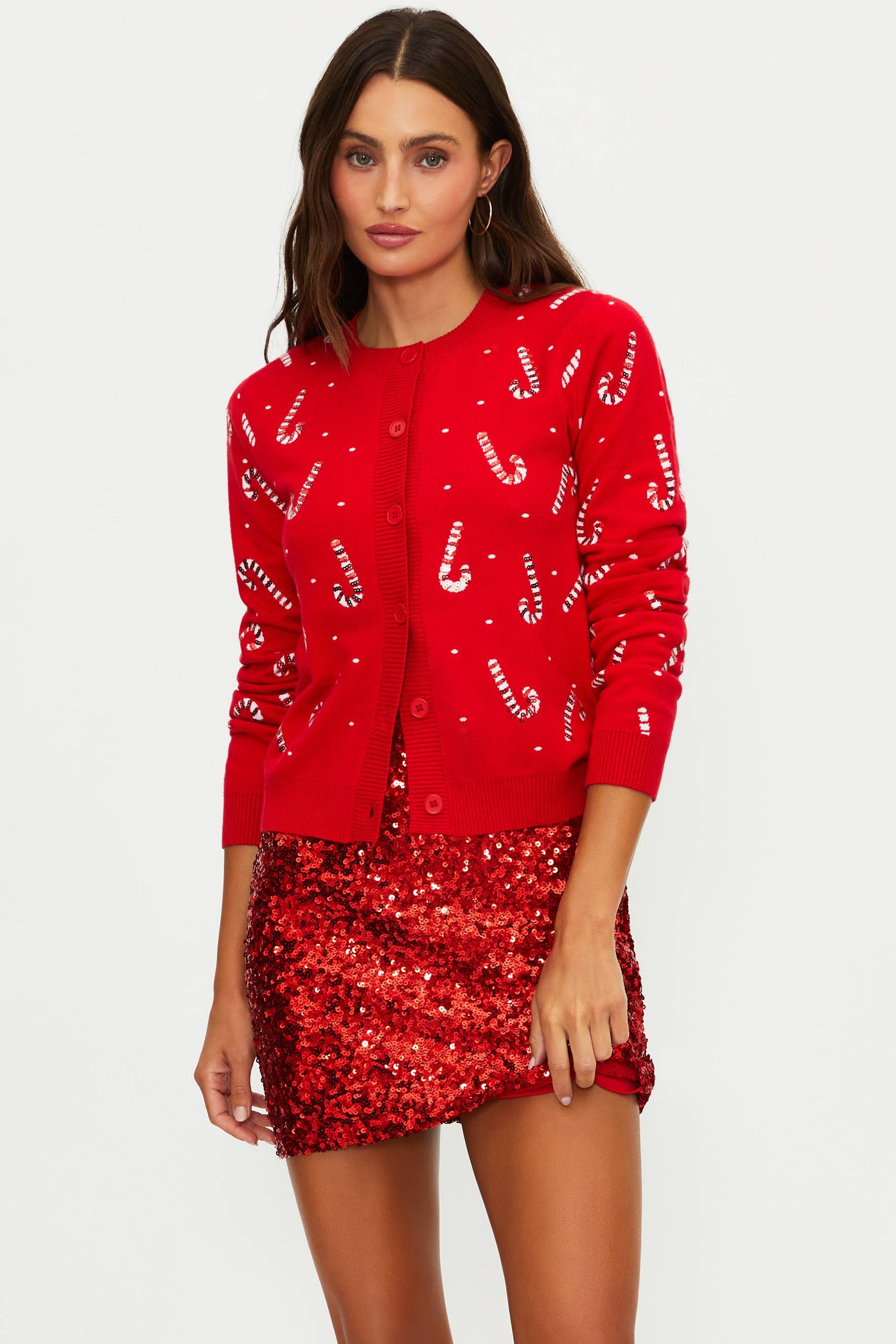 Woman wearing a red sequin skirt and matching cardigan on a white background