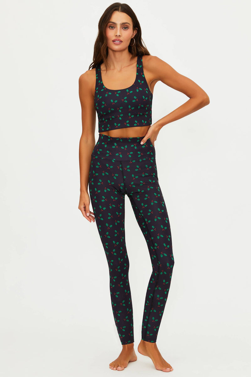 Woman wearing a black patterned sports bra and leggings on a white background