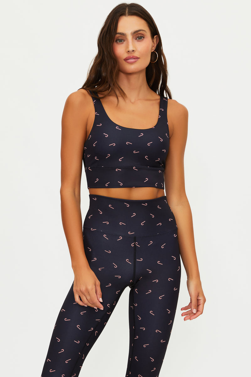 Woman wearing a navy blue sports bra and leggings with pink patterns on a white background