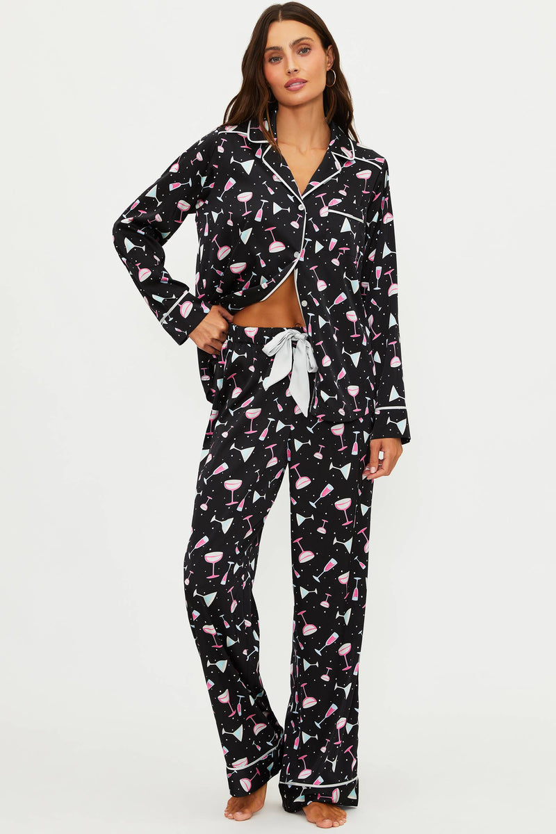 Woman wearing a black pajama set with pink flamingo pattern on a white background