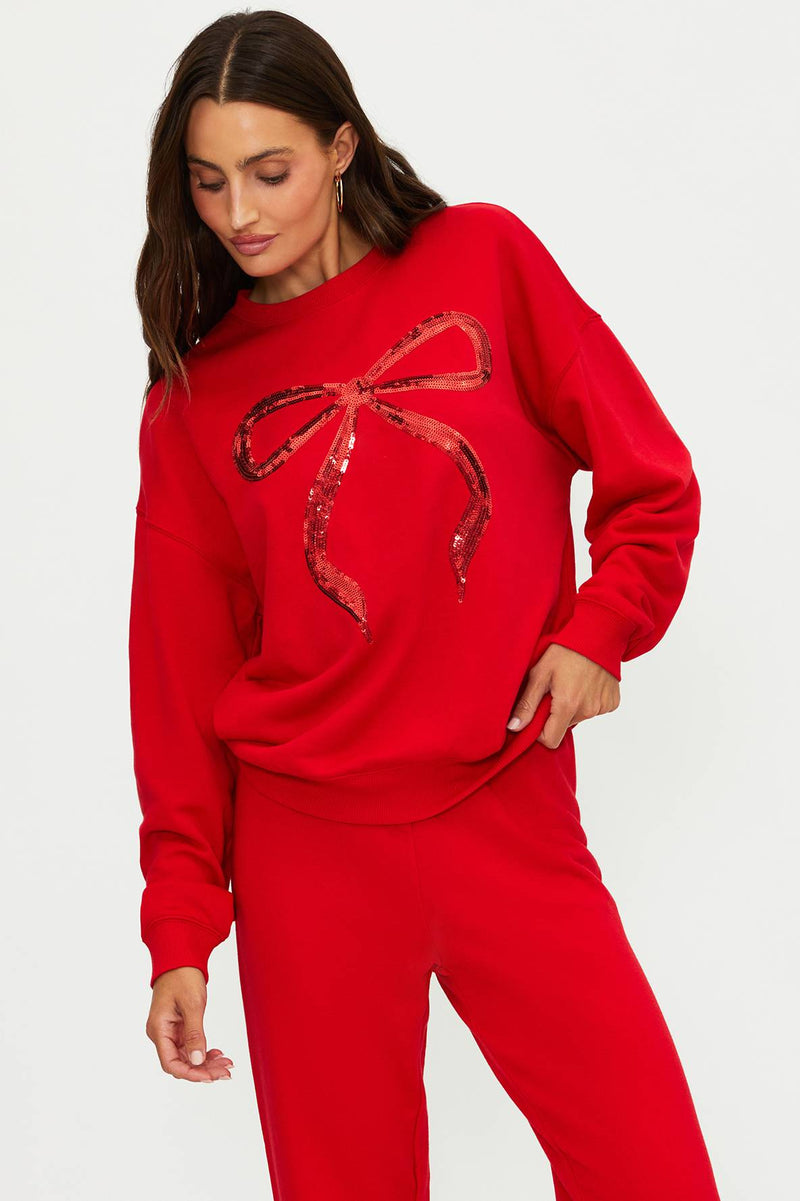 Woman wearing a red sweater with a bow design on a white background