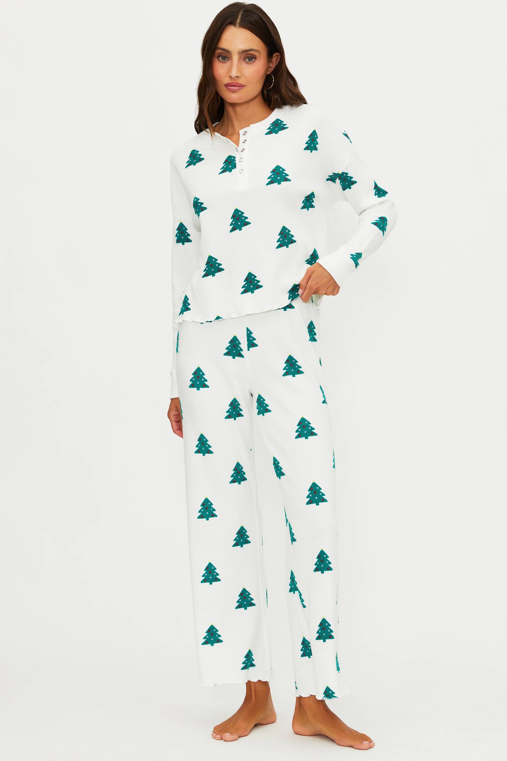 Woman wearing a white pajama set with green tree patterns on a white background
