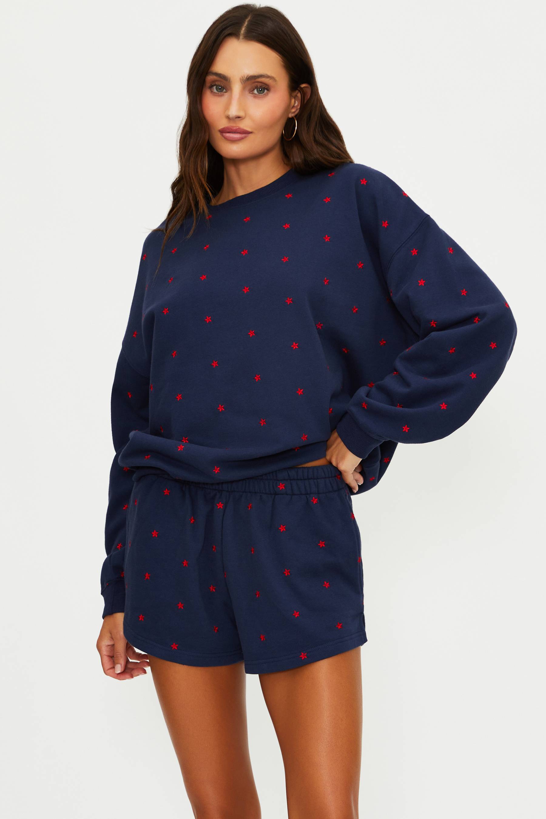 Woman wearing a navy sweatshirt and shorts with red polka dots on a white background