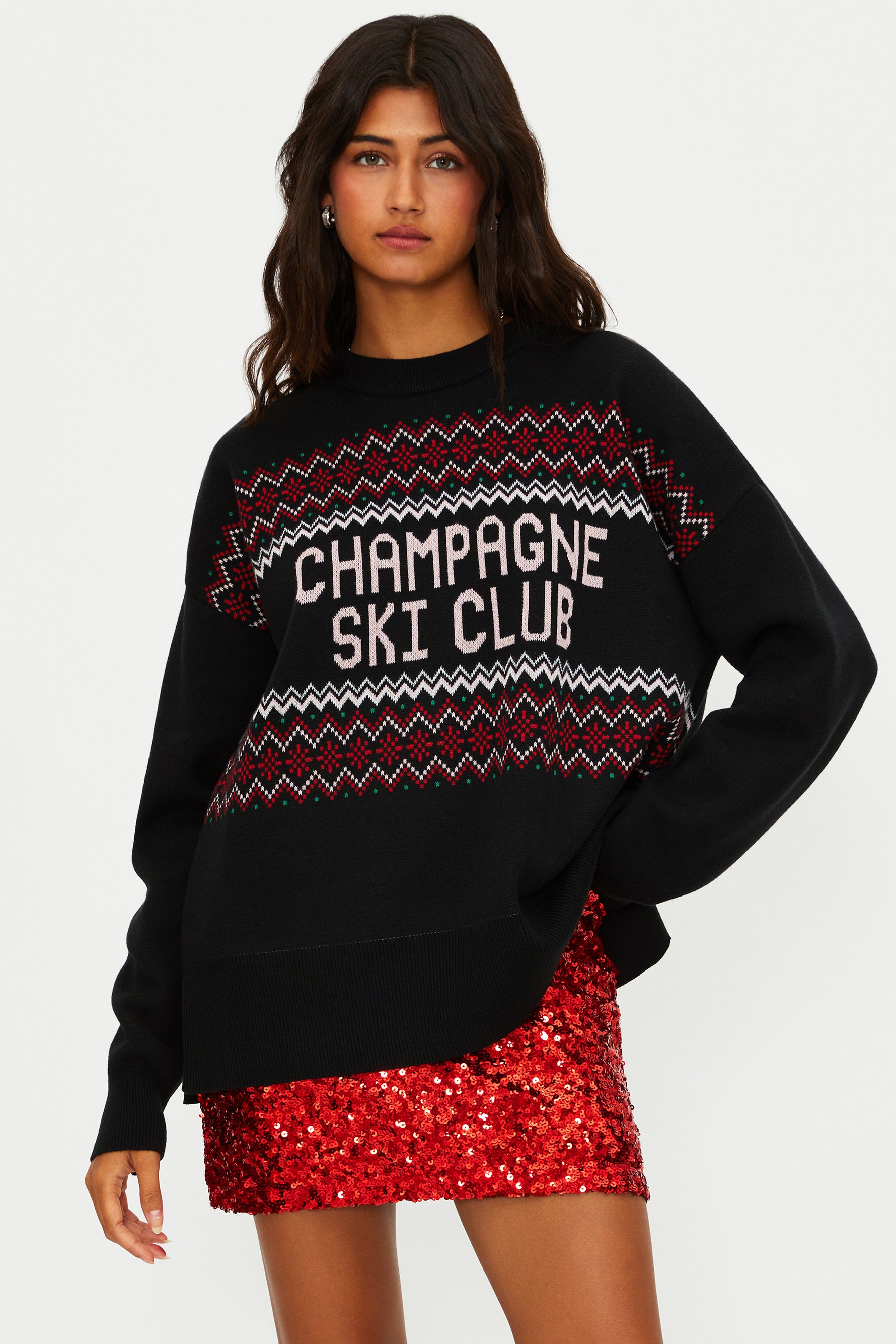 Woman wearing a black sweater with 'Champagne Ski Club' text and a red sequin skirt on a white background