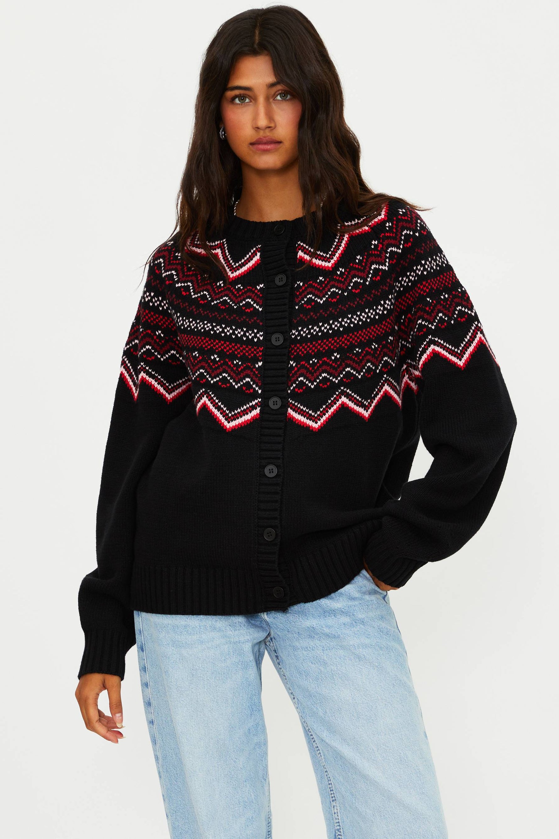 Woman wearing a black sweater with red and white pattern on a white background