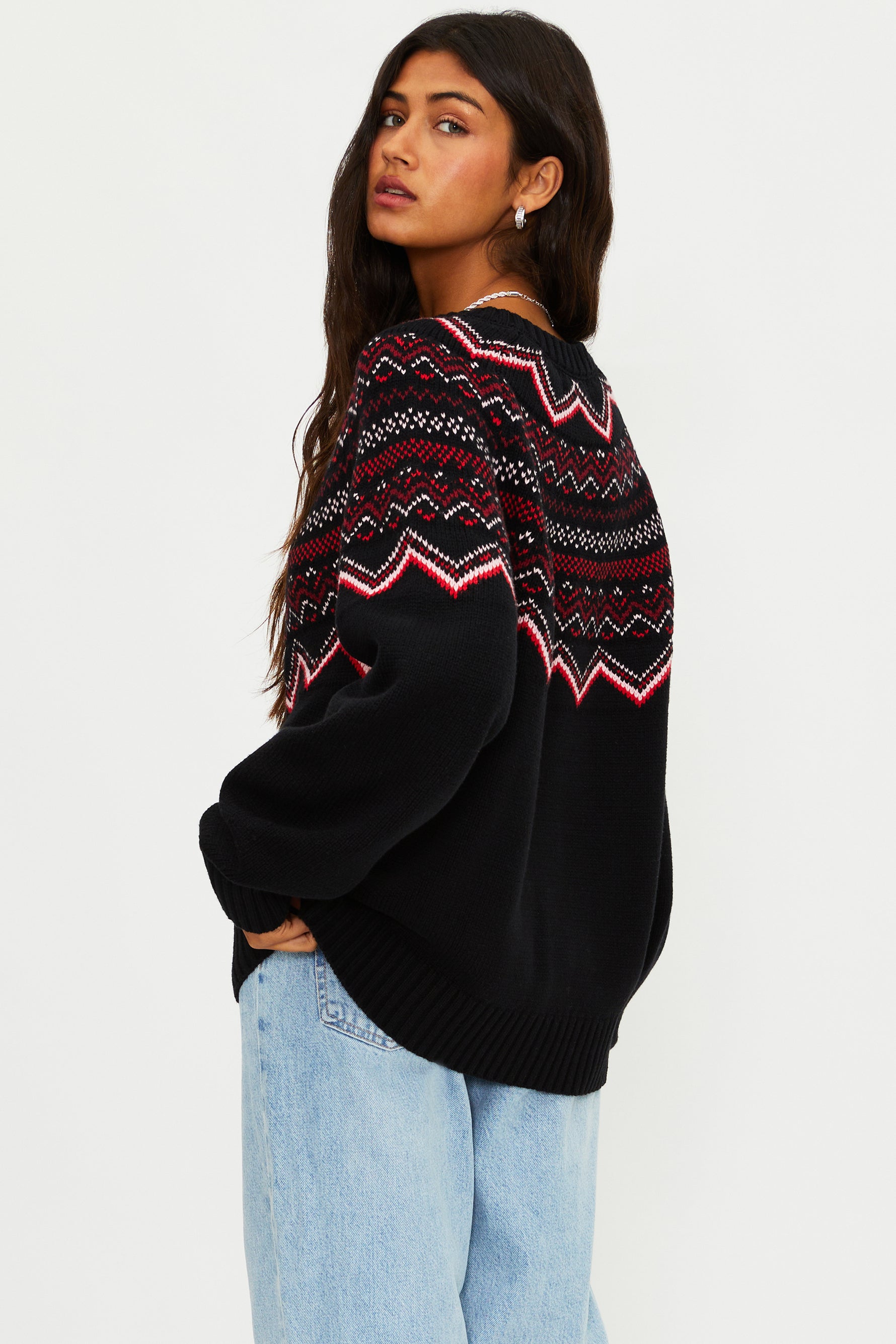 Woman wearing a black sweater with a colorful pattern on a white background