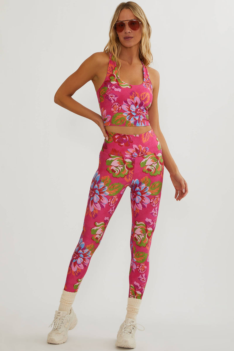 Woman wearing a pink floral sports bra and leggings set on a white background