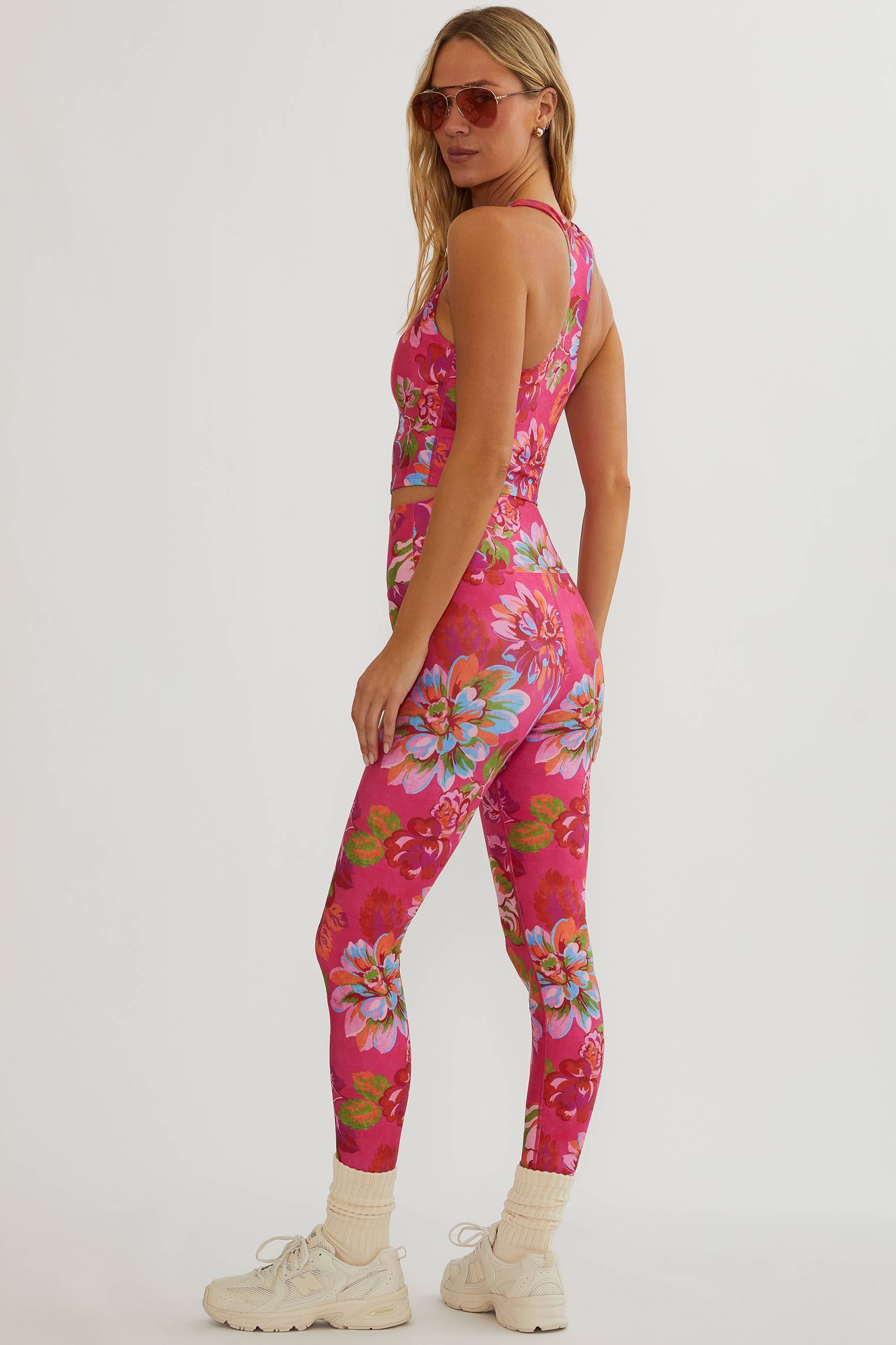 Woman wearing a pink floral jumpsuit on a white background