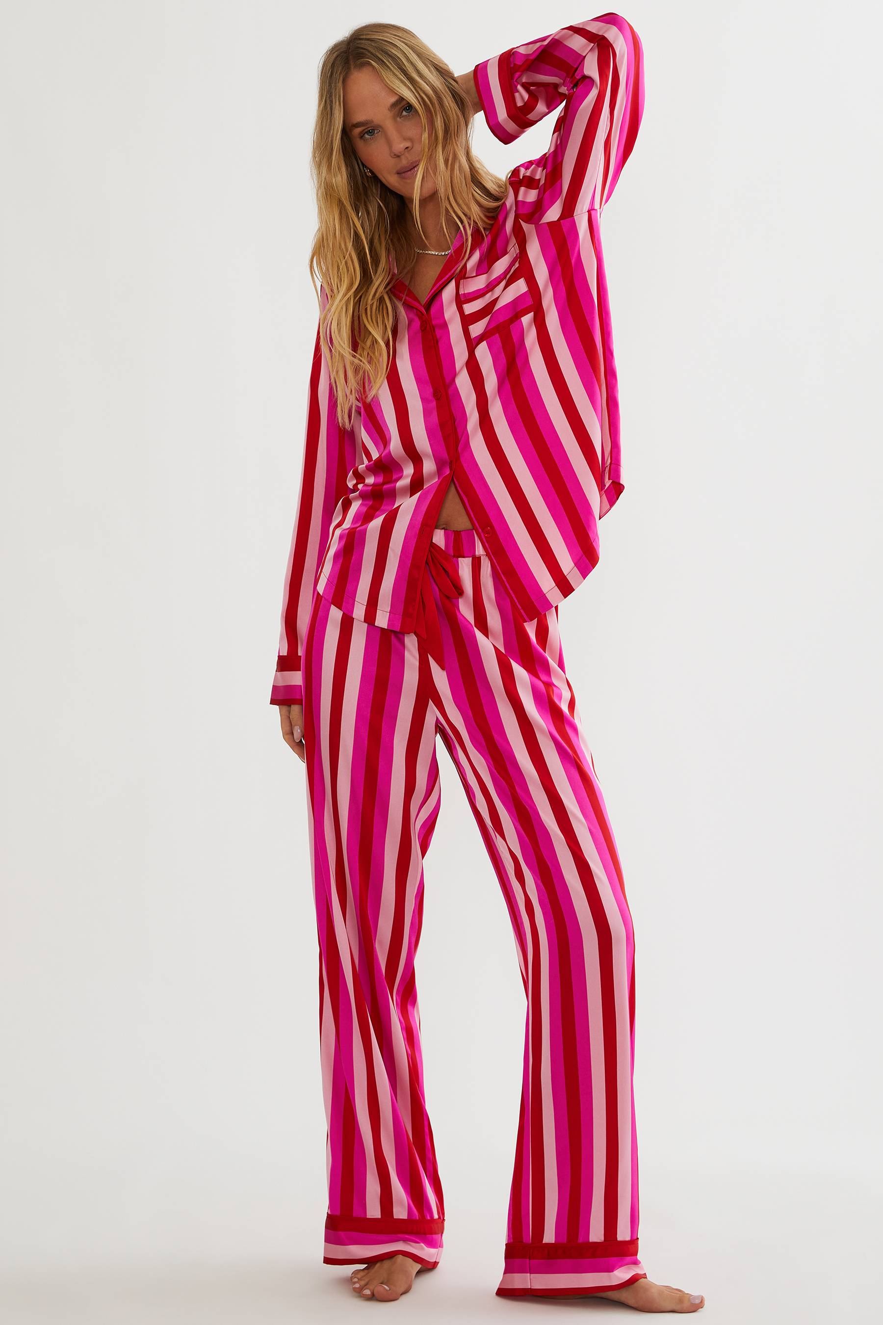 Woman wearing a pink and white striped pajama set on a white background