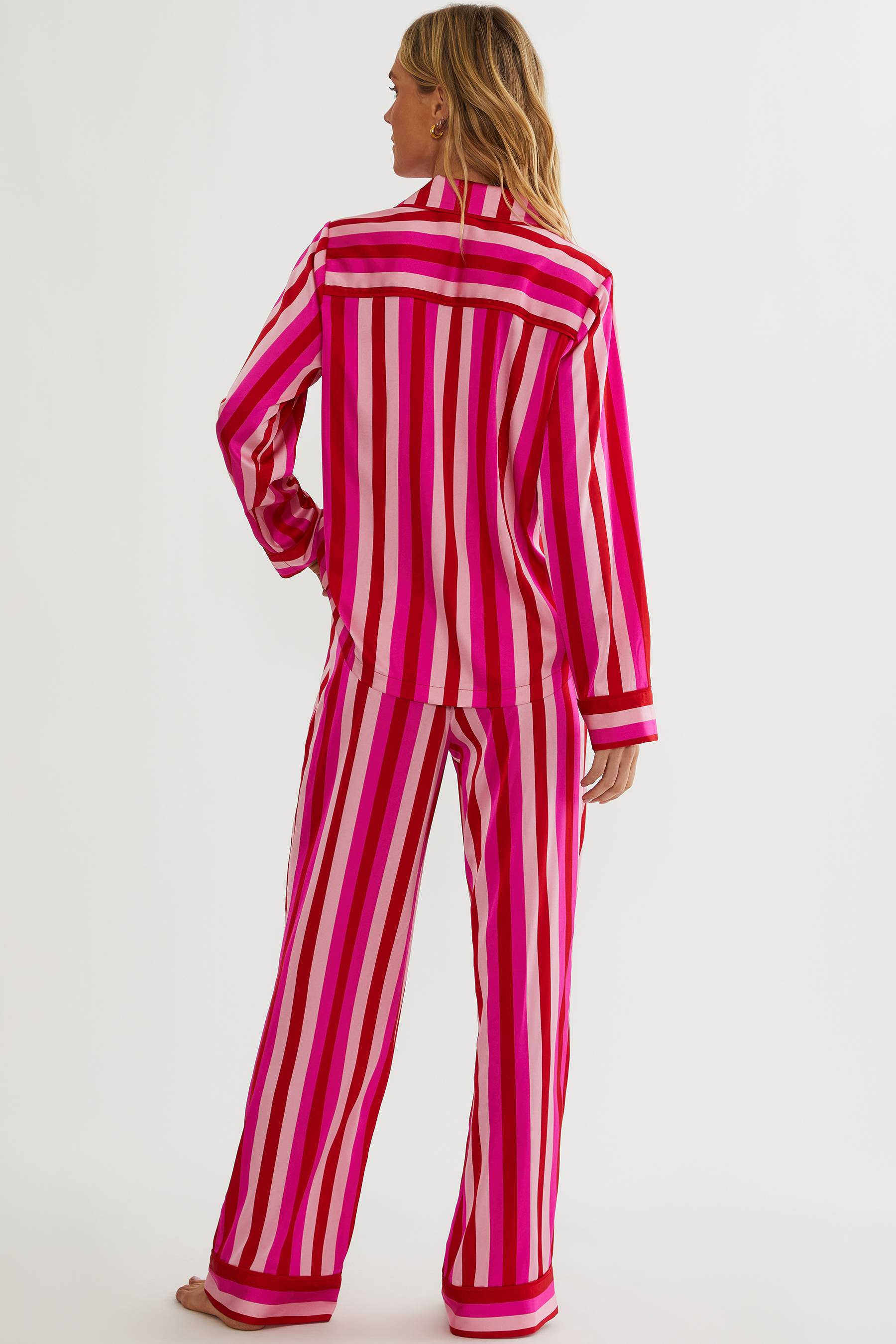 Person wearing a pink and red striped pajama set on a white background