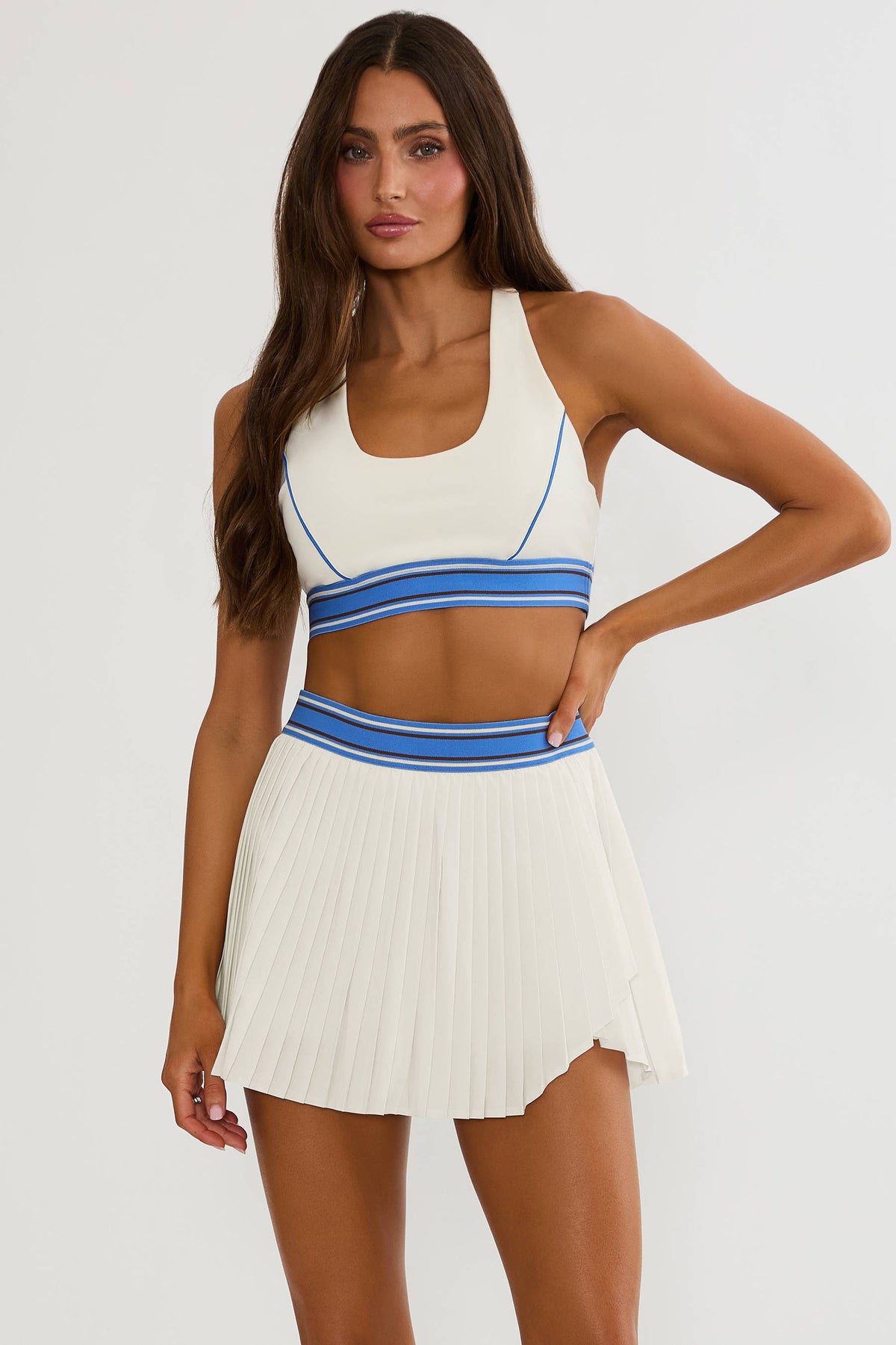Woman wearing cream racerback sports bra with blue lining. 