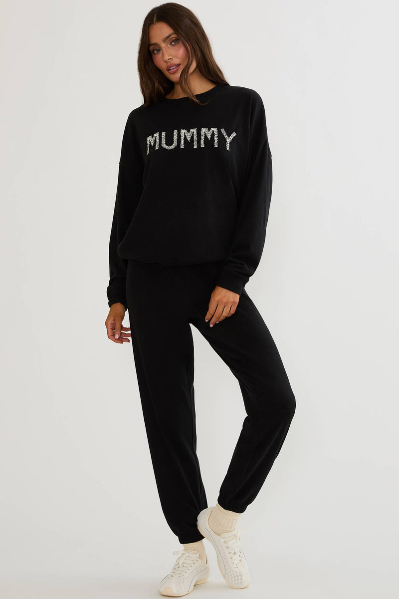 Black sweatpants worn by a woman on a plain white background. 