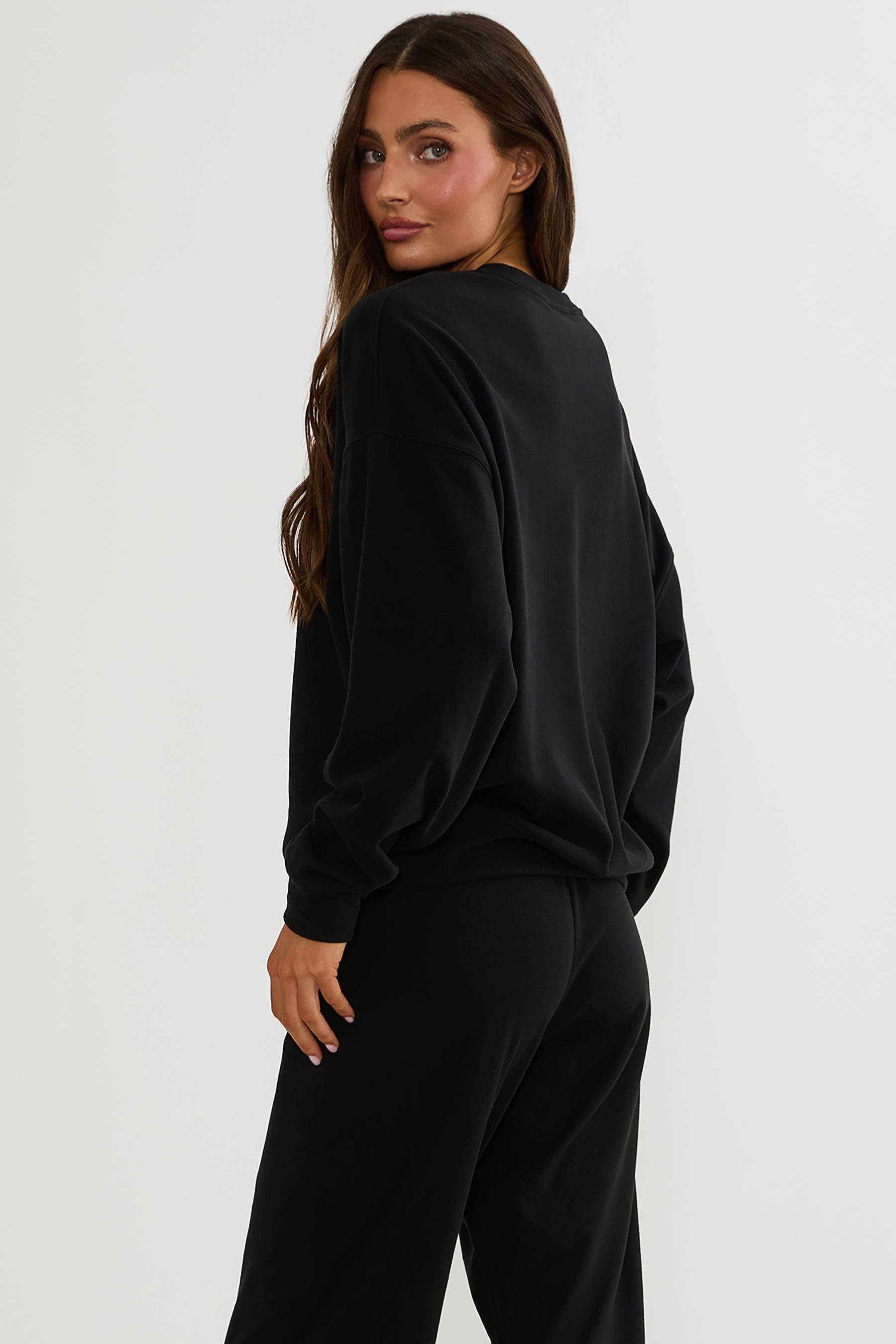 Black oversized sweatshirt with Halloween text "mummy" worn by a woman on a plain white background. 