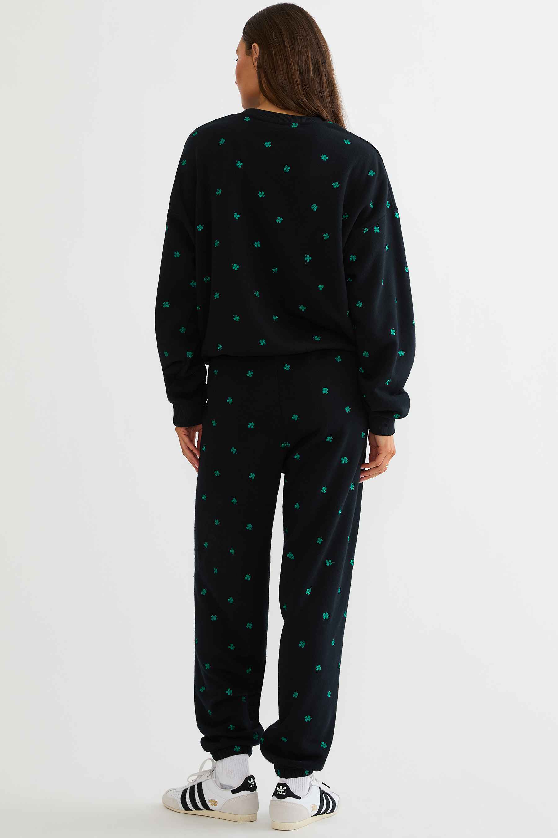 Person wearing a black tracksuit with green patterns on a white background