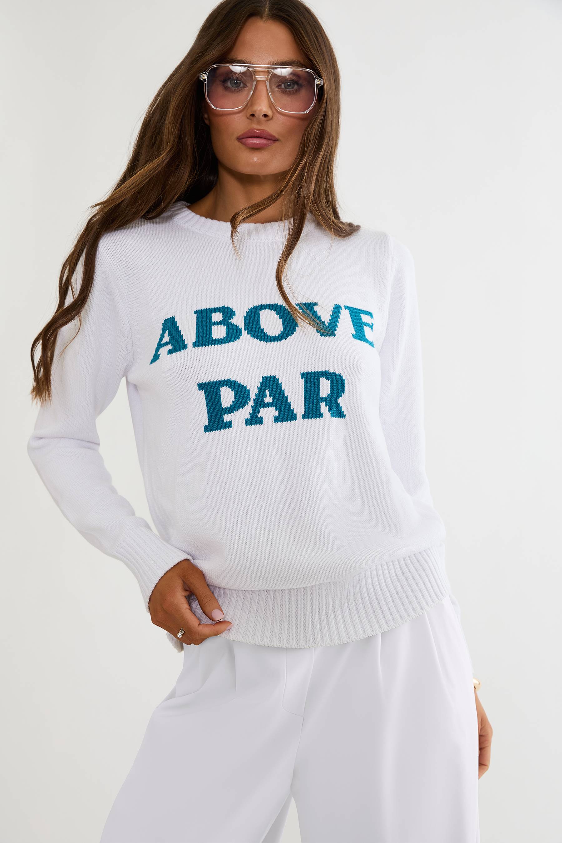 Woman wearing a white sweater with 'ABOVE PAR' text on a white background