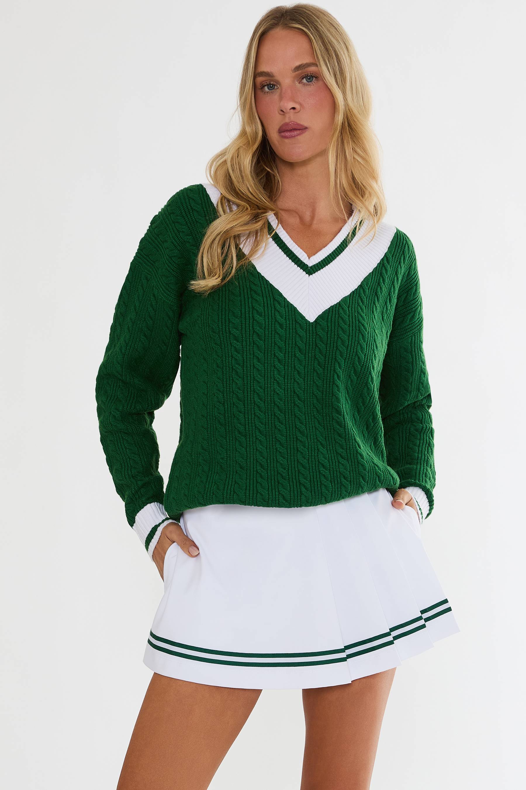Woman wearing a green and white sweater with a white skirt on a white background