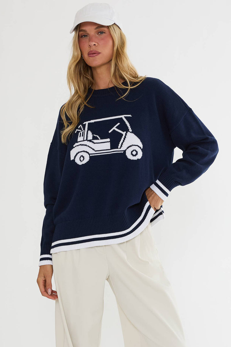 Woman wearing a navy sweater with a white graphic design on a white background