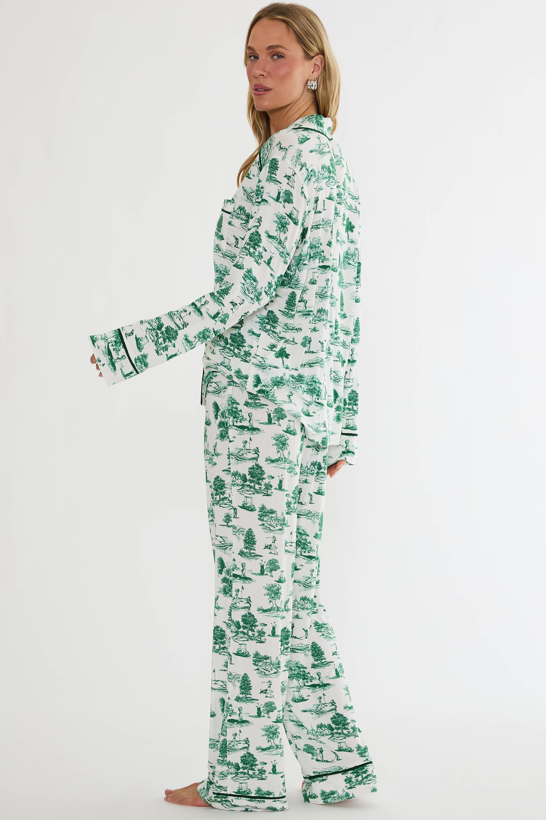 Woman wearing a green and white patterned pajama set on a white background
