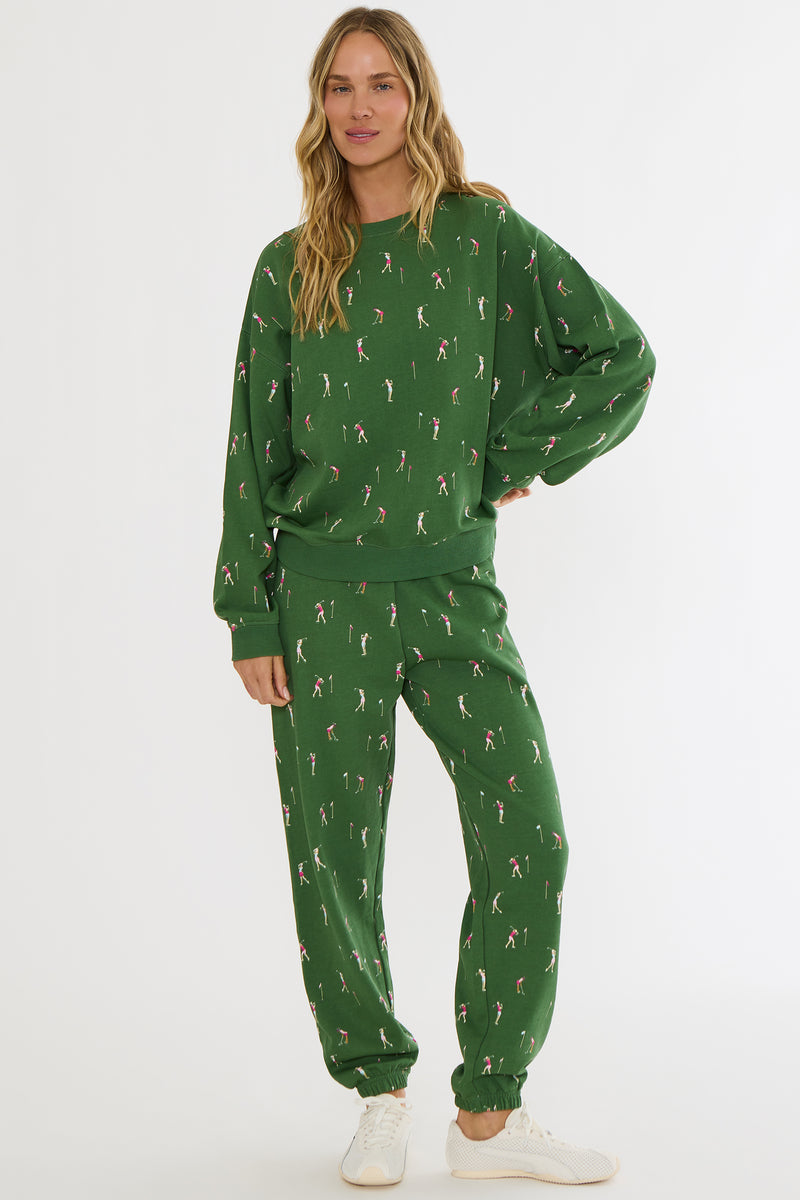 Person wearing a green patterned sweatshirt and pants set on a white background