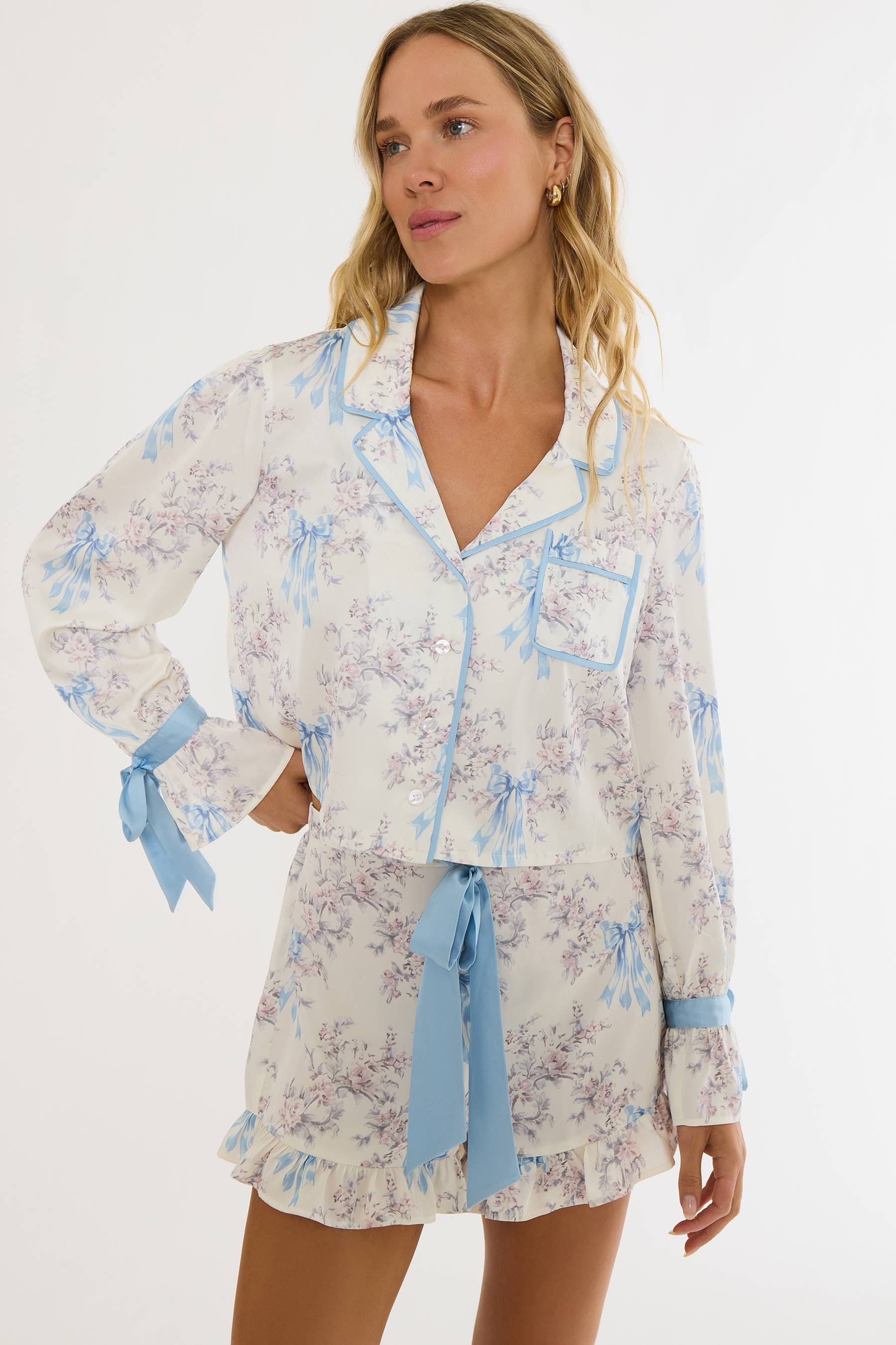 Woman wearing a floral pajama set with blue accents on a white background