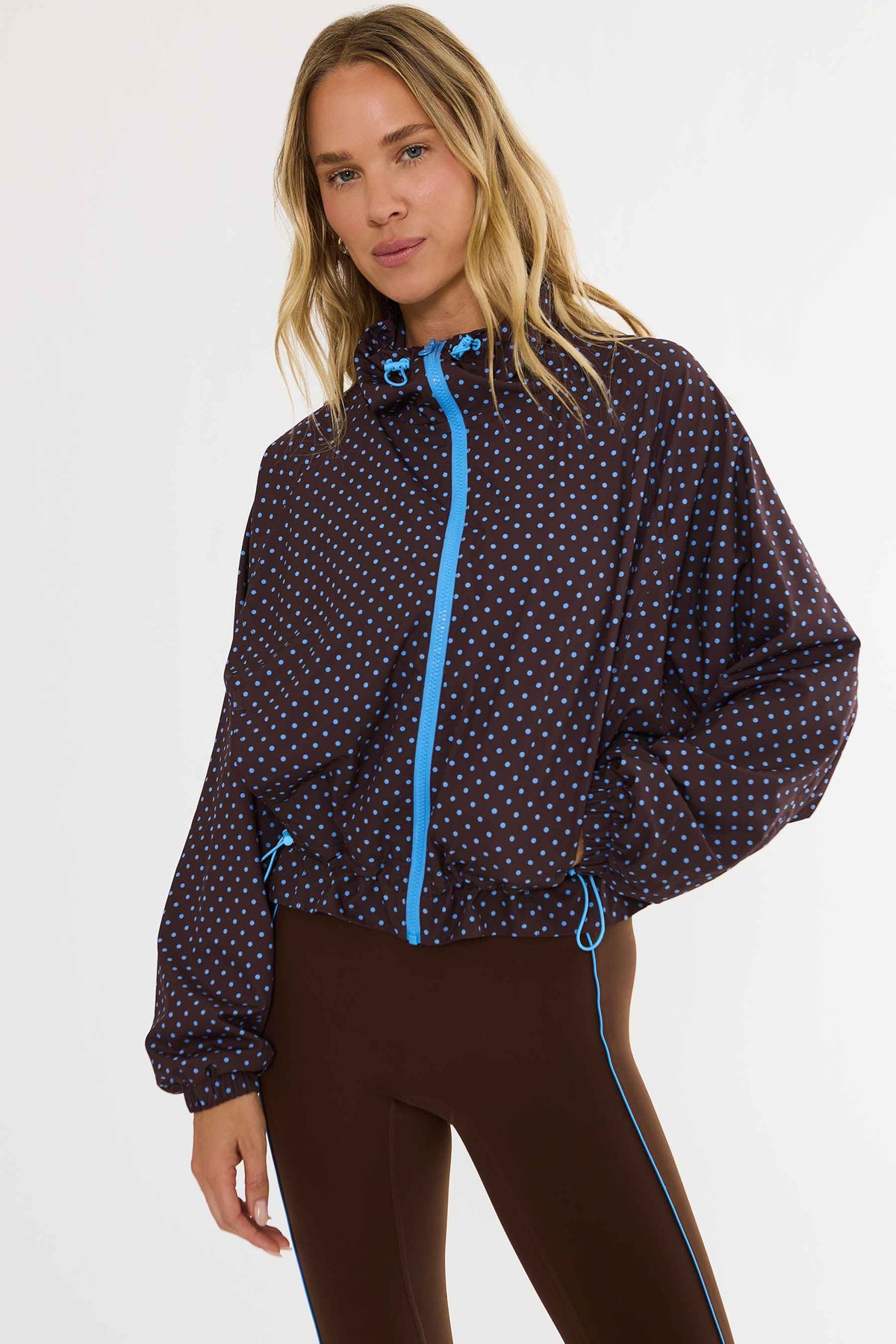 Woman wearing brown zip up with blue polka dots zip up track jacket.