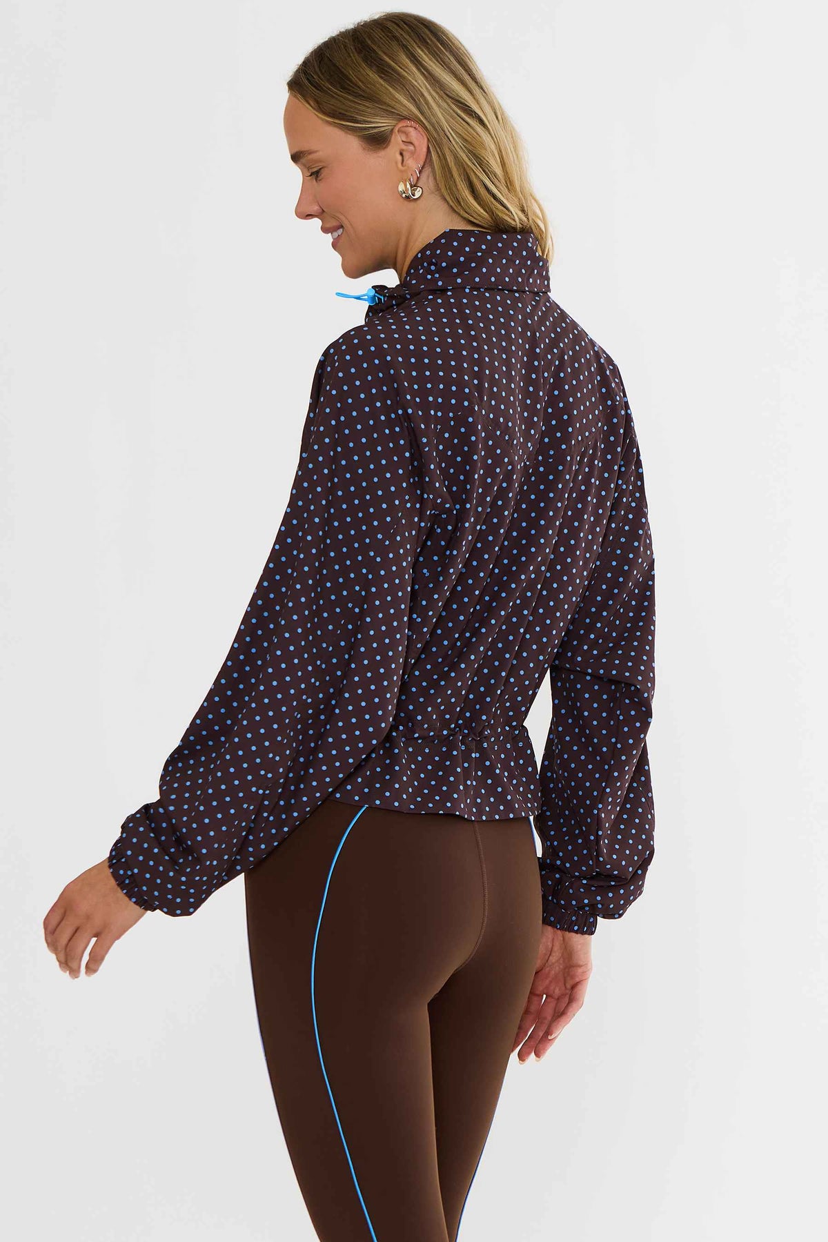 Woman wearing brown zip up with blue polka dots zip up track jacket.