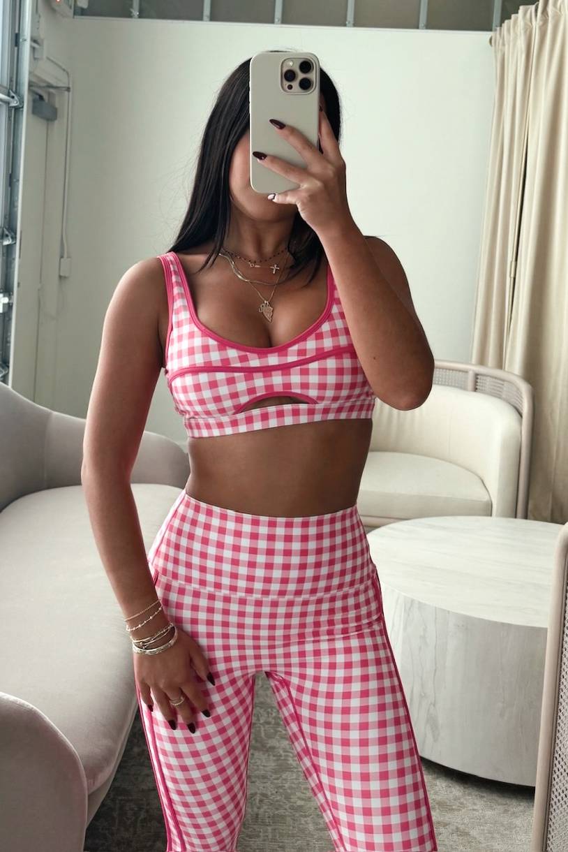Person wearing a pink and white checkered outfit taking a mirror selfie.