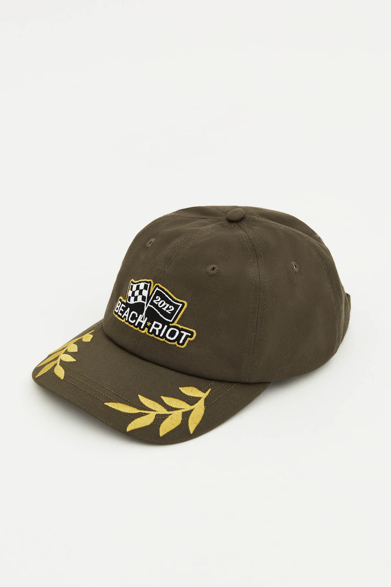 An olive green dad hat with the Beach Riot logo on the front and decorative yellow embroidery on the sides.