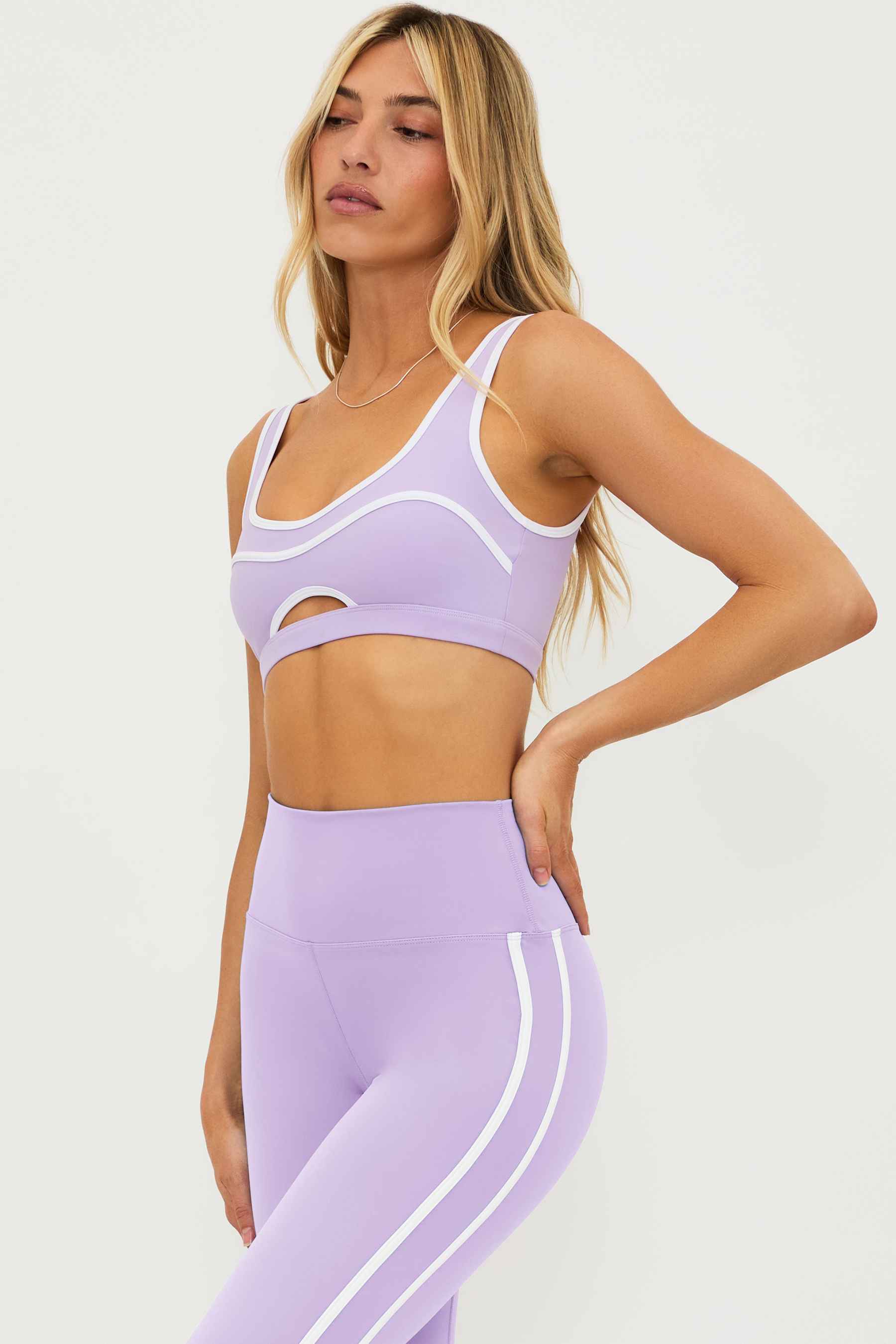 lavender pleated tennis skirt with a with contrast trim and a matching lavender sports bra with a cutout detail and white contrast trim